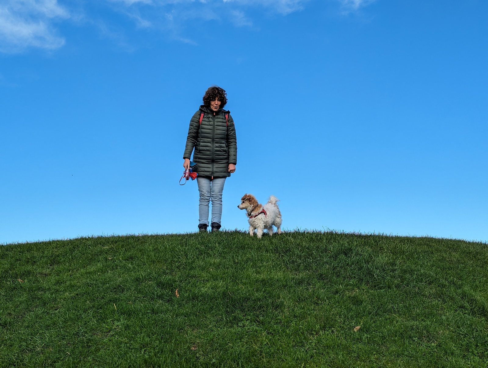 Priska and Lillie the dog on the grass at Gretna Green under a blue sky.