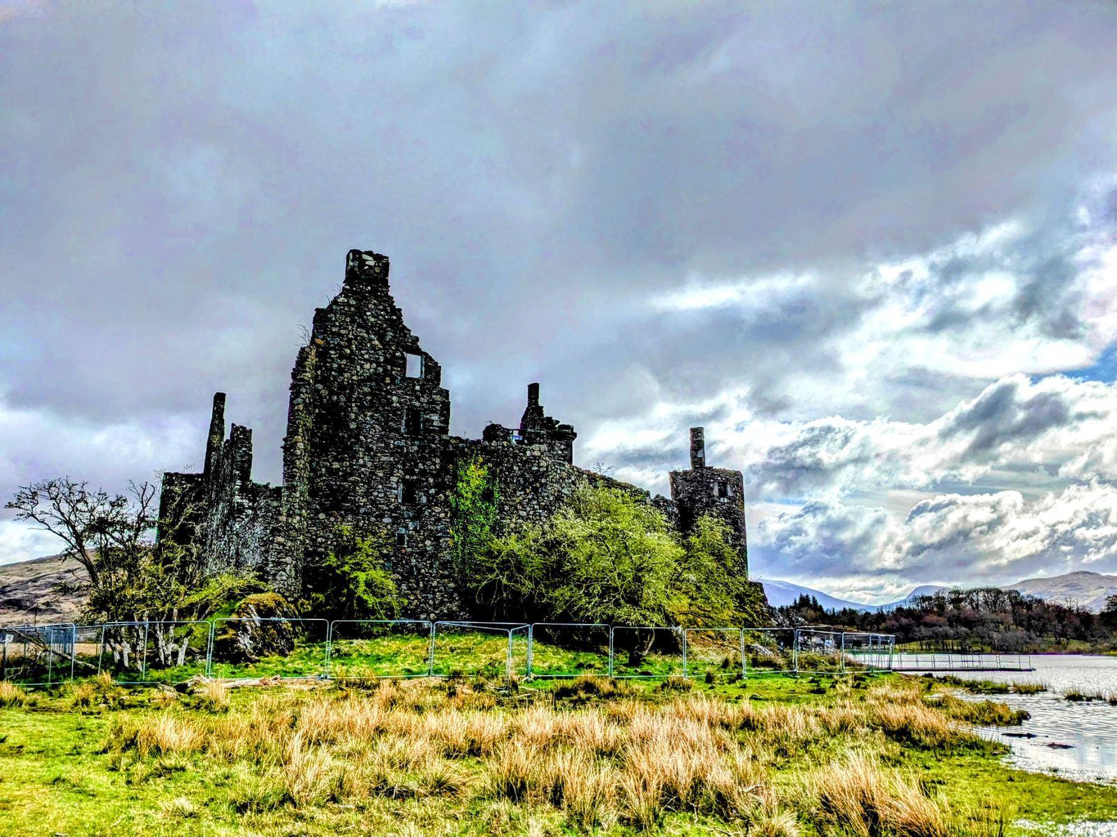 The tower house of Kilchurn Castle, ivy-streaked stone against a blue sky.