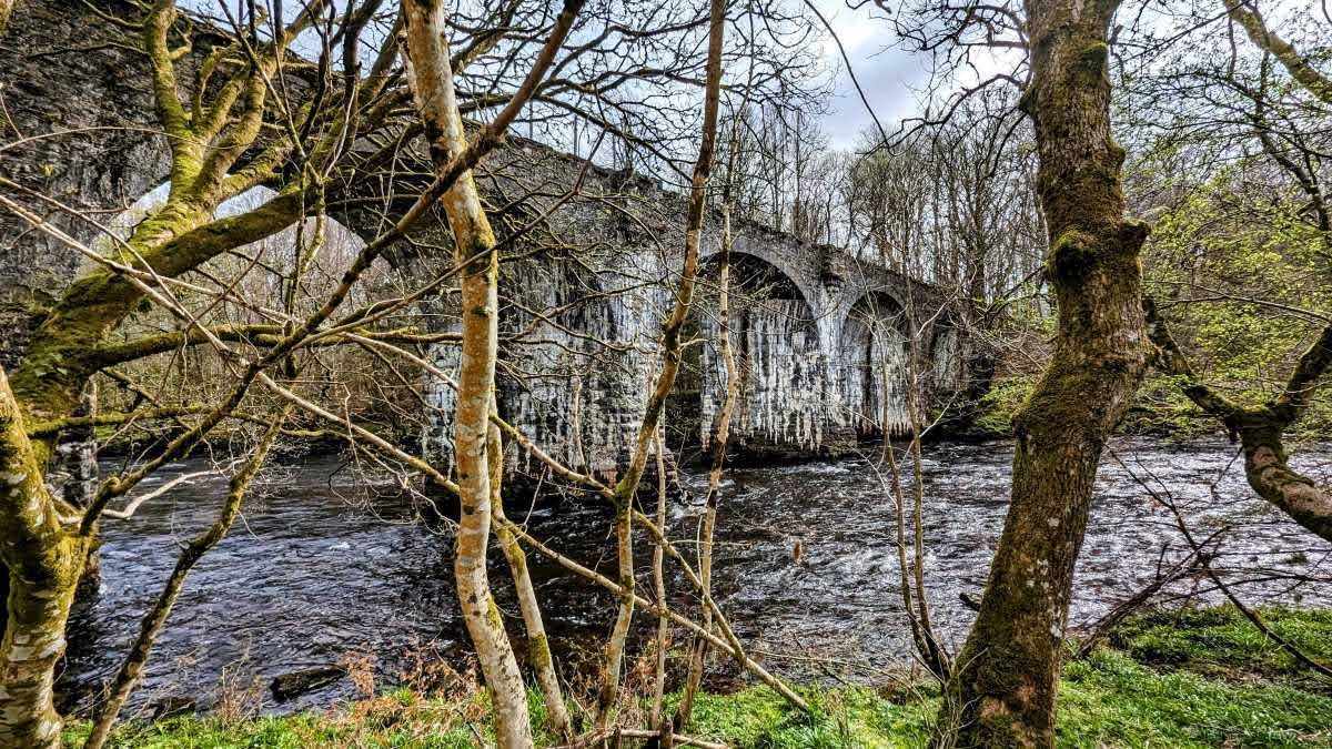 A graceful multi-arched stone bridge over the River Dochart at Killin, framed by bare winter trees.
