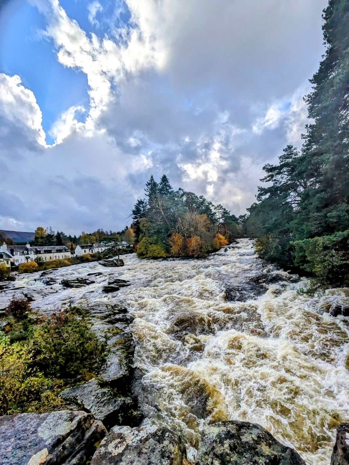 The Falls of Dochart at Killin in full autumn spate, white water crashing over the rock ledges with autumn trees along the banks.