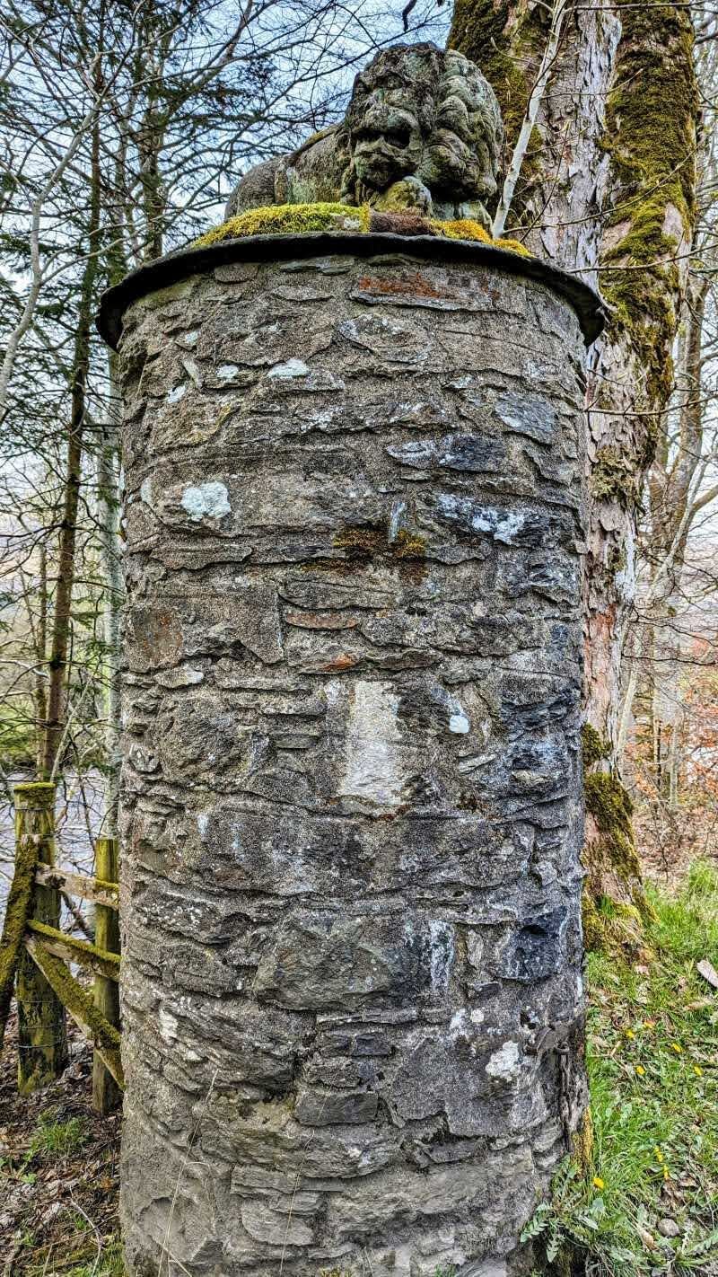 A tall carved stone gatepost topped with a weathered carved figure at the entrance to the Kinnell Estate, Killin.