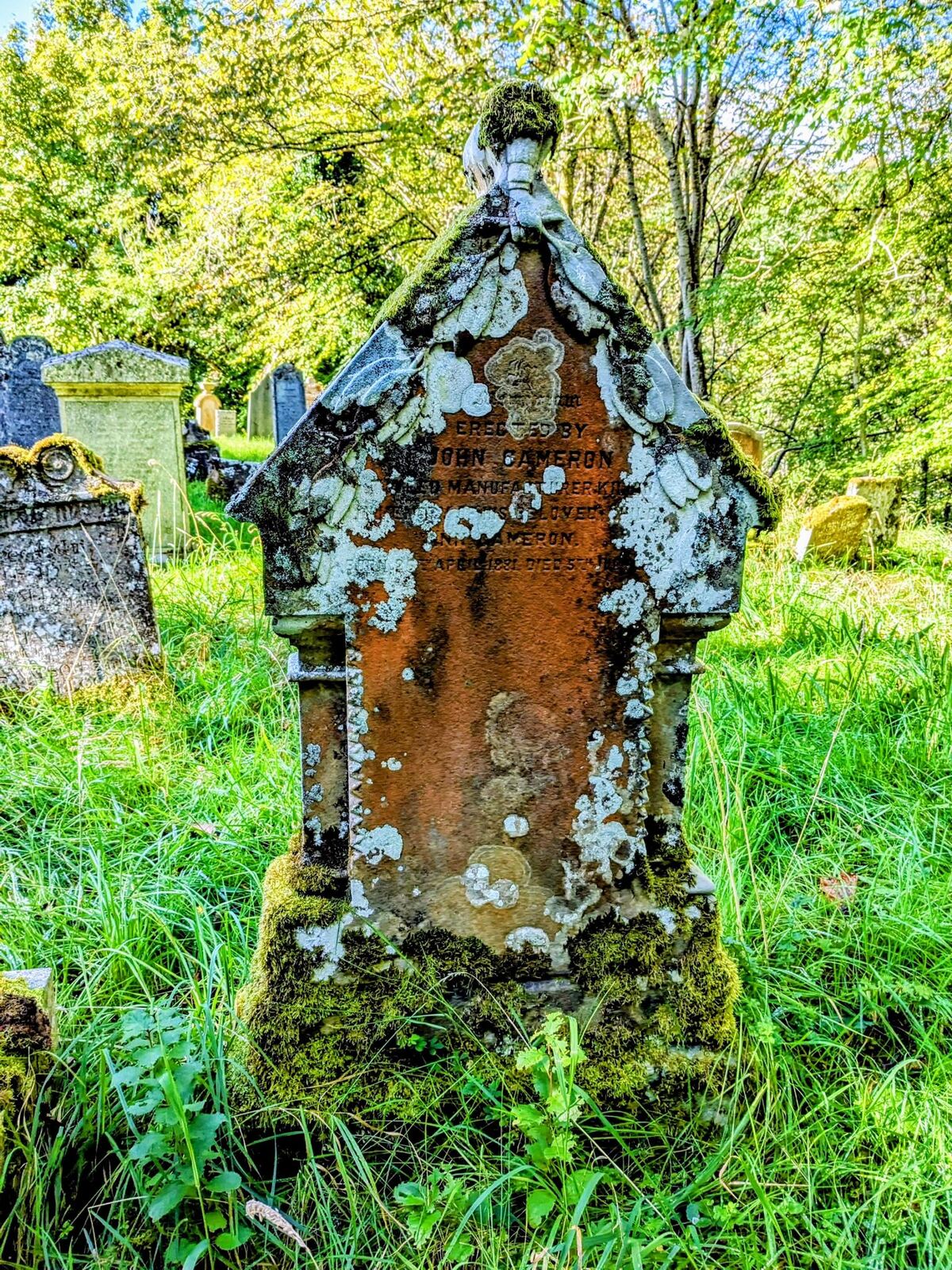 An old, ornate, lichen-covered headstone standing in the kirkyard at Killin.