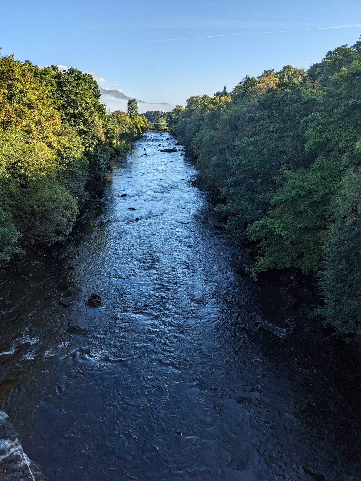 The river at Killin running between green, leafy wooded banks.