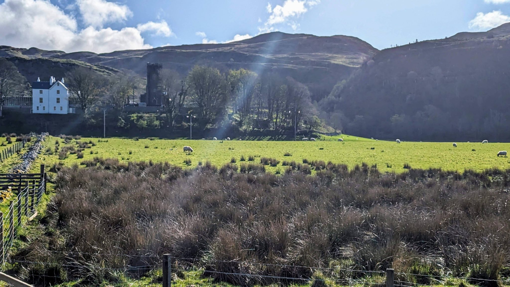 A wide view down Kilmartin Glen, green fields and hills, with a ruined tower on the skyline.