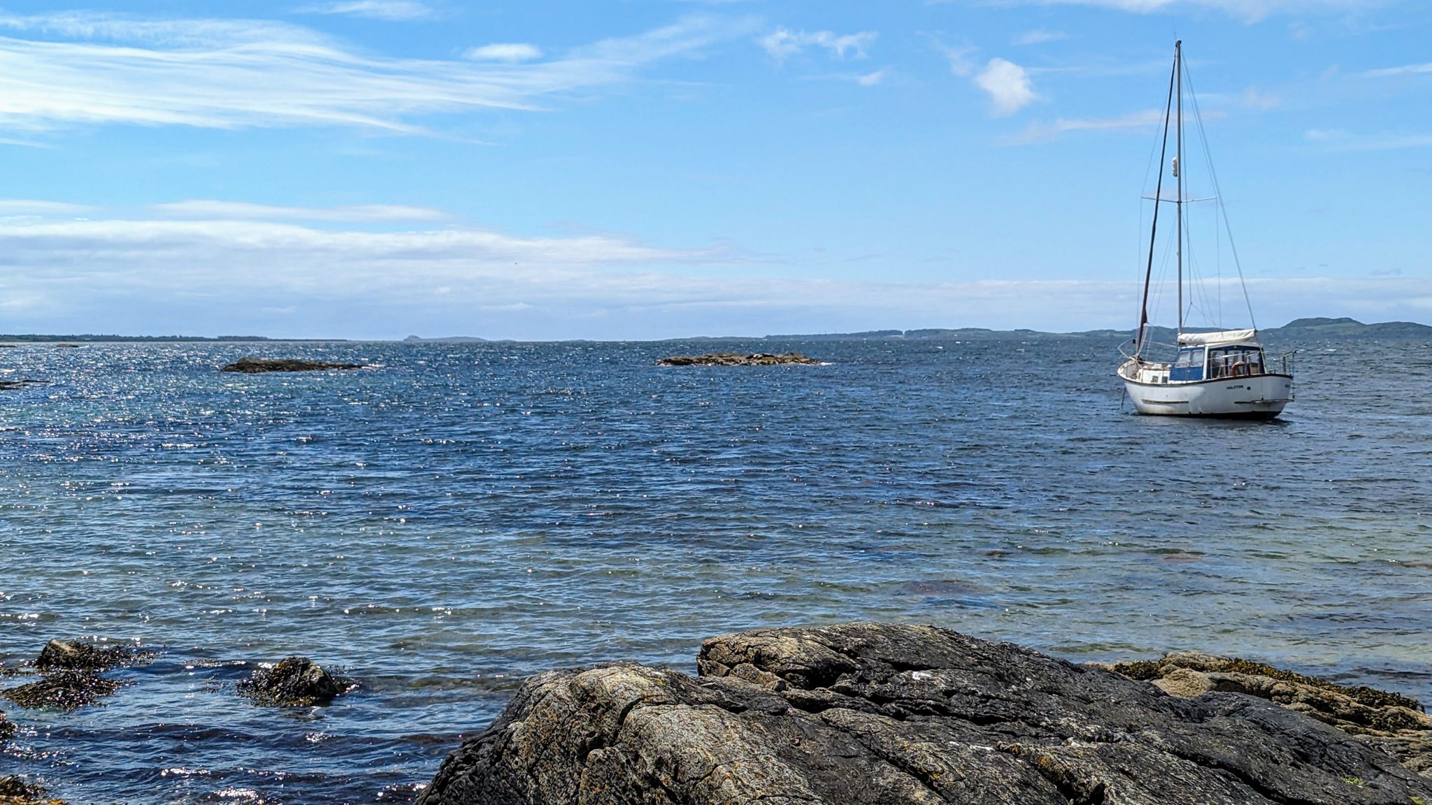 Yachts anchored in the calm bay off the east Kintyre coast, islands on the horizon.