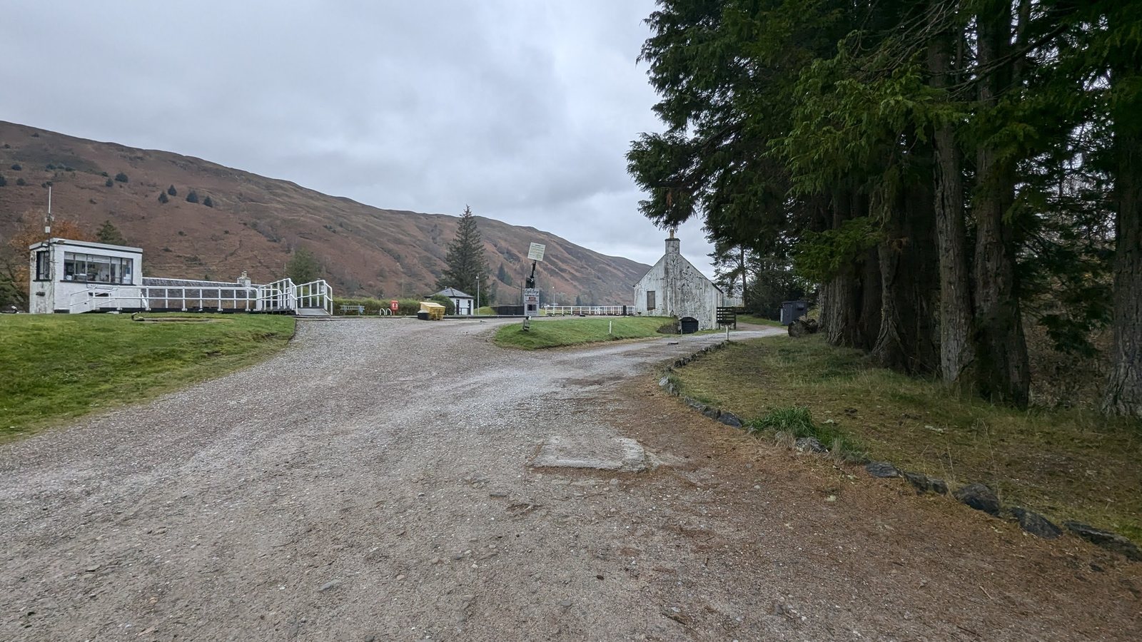 A gravel track lined with trees leading down to the canal buildings at Laggan Locks.
