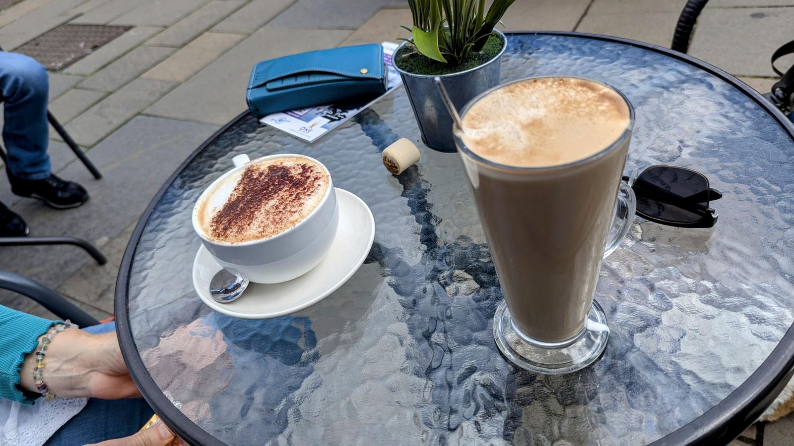 A cappuccino and a tall latte on an outdoor café table in Linlithgow.