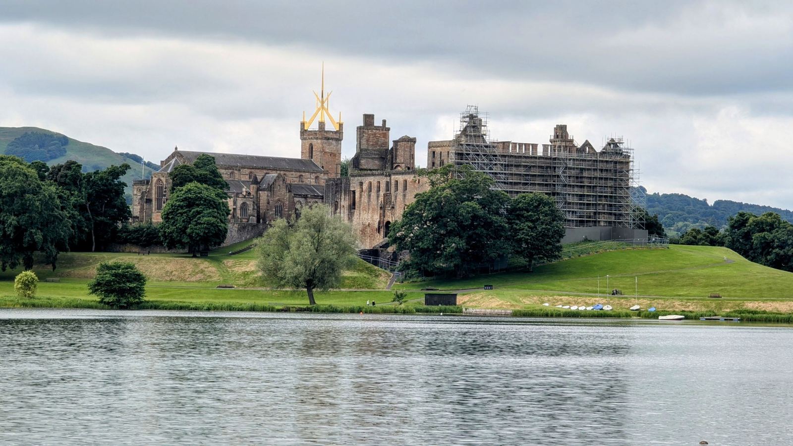 Linlithgow Palace and St Michael's crown spire reflected across the calm water of Linlithgow Loch.