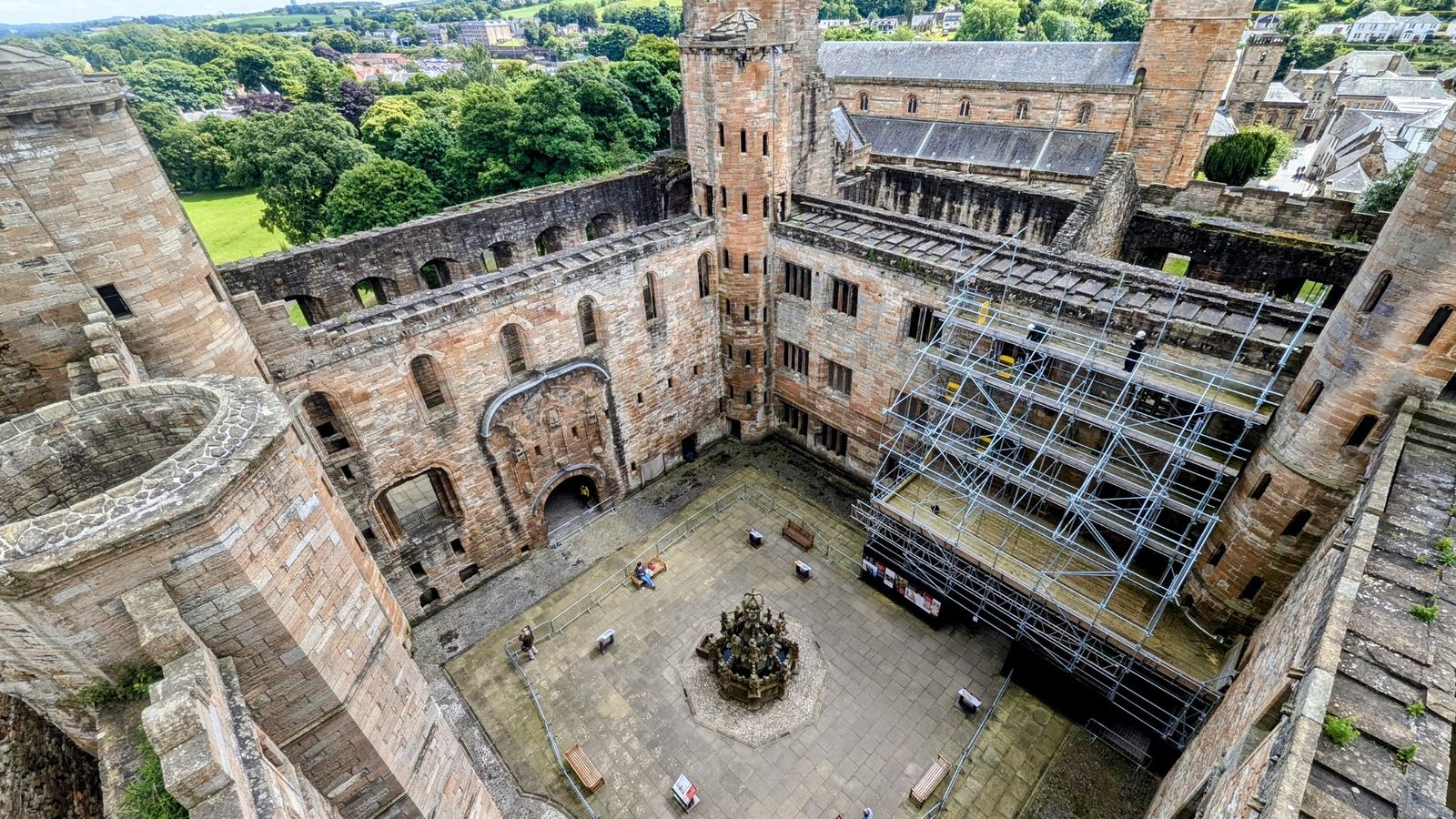Looking down into the courtyard of Linlithgow Palace from an upper floor, the King's Fountain small in the centre and ruined ranges all around.
