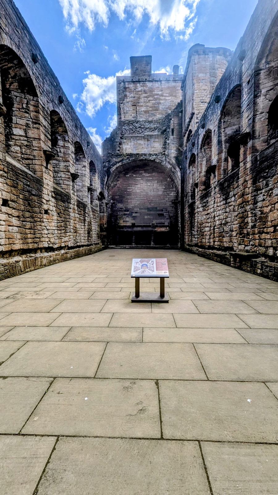 The Great Hall of Linlithgow Palace, a vast roofless chamber with a huge stone fireplace at the far end.