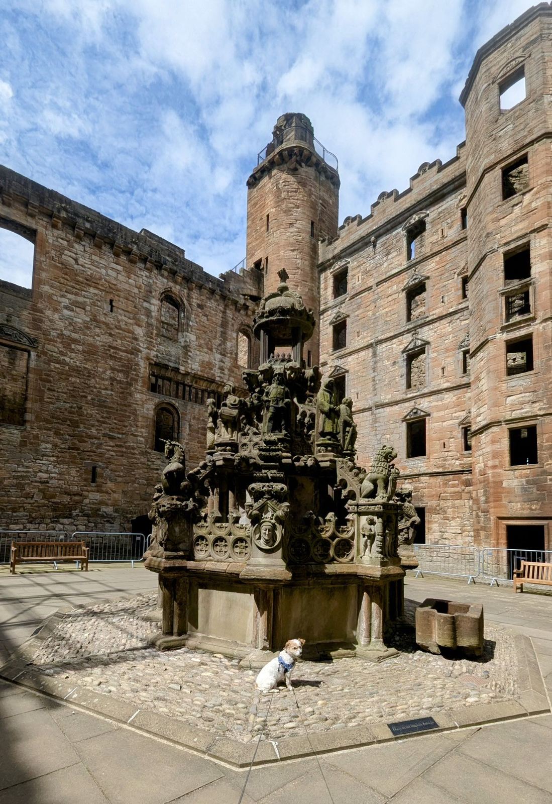 The ornately carved stone King's Fountain in the courtyard of ruined Linlithgow Palace, the tall palace tower behind.