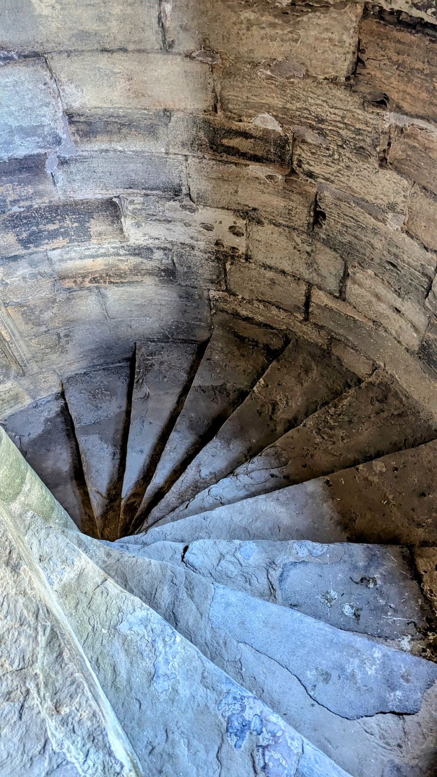 Looking up a stone spiral turnpike staircase inside Linlithgow Palace.