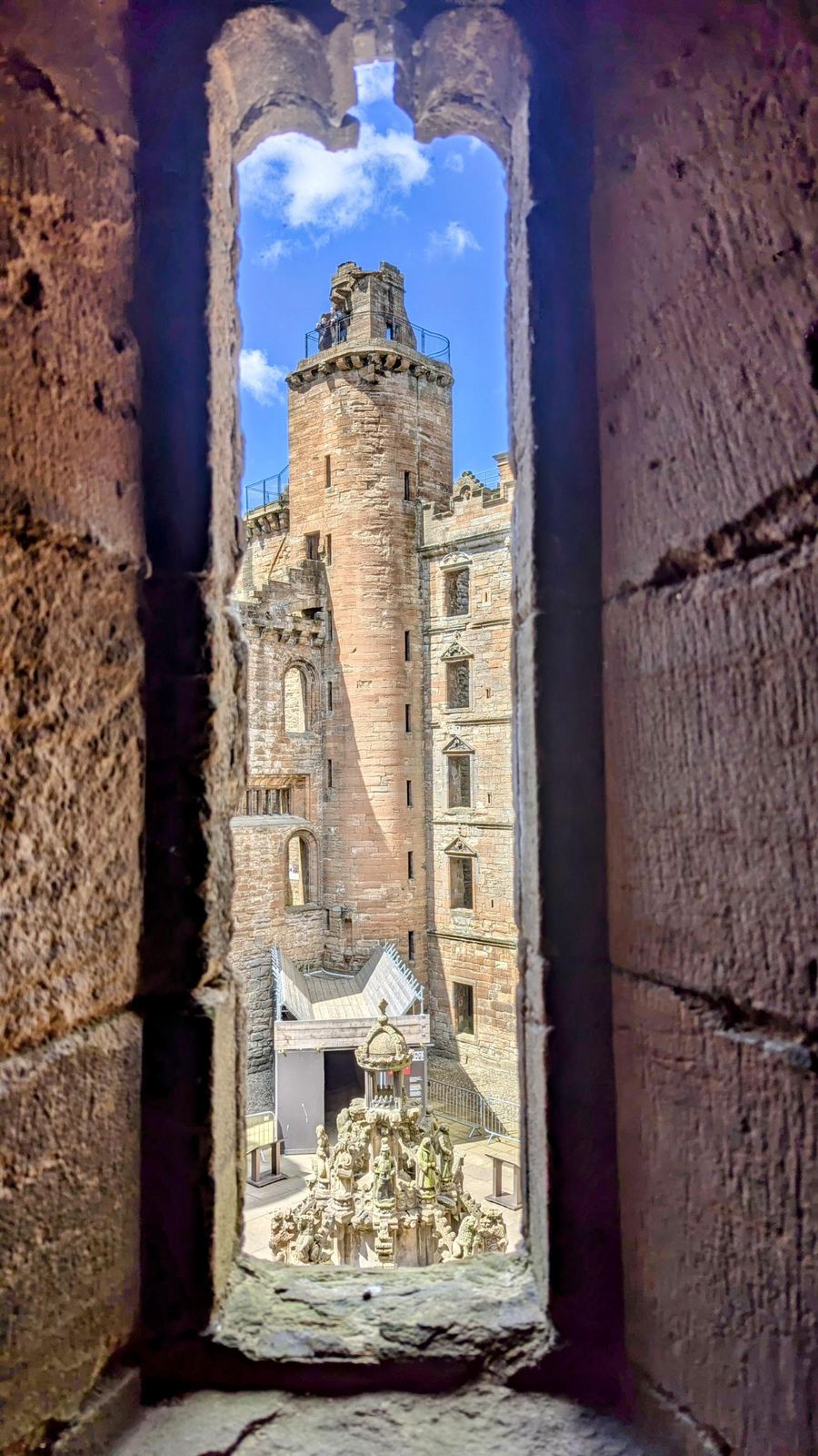 Close view of the corner turrets and towers of Linlithgow Palace against a blue sky.