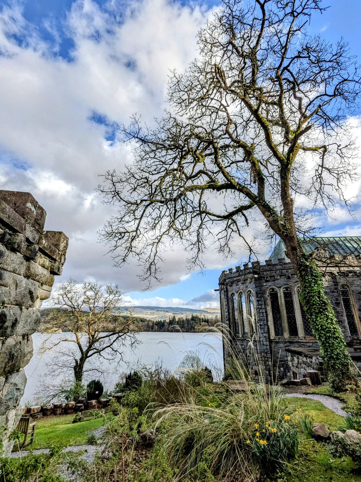 The exterior of St Conan&rsquo;s Kirk with an old tree and Loch Awe stretching away behind.