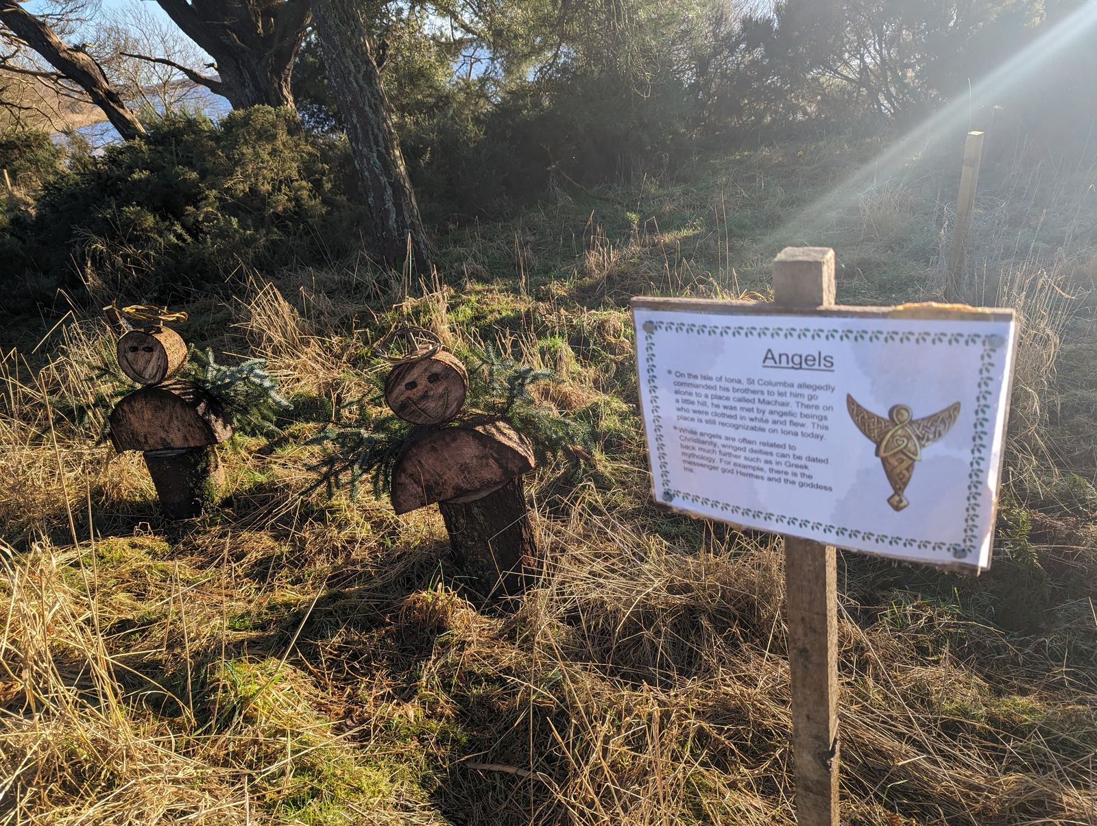 A carved wooden figure and story board on the trail at Loch Leven