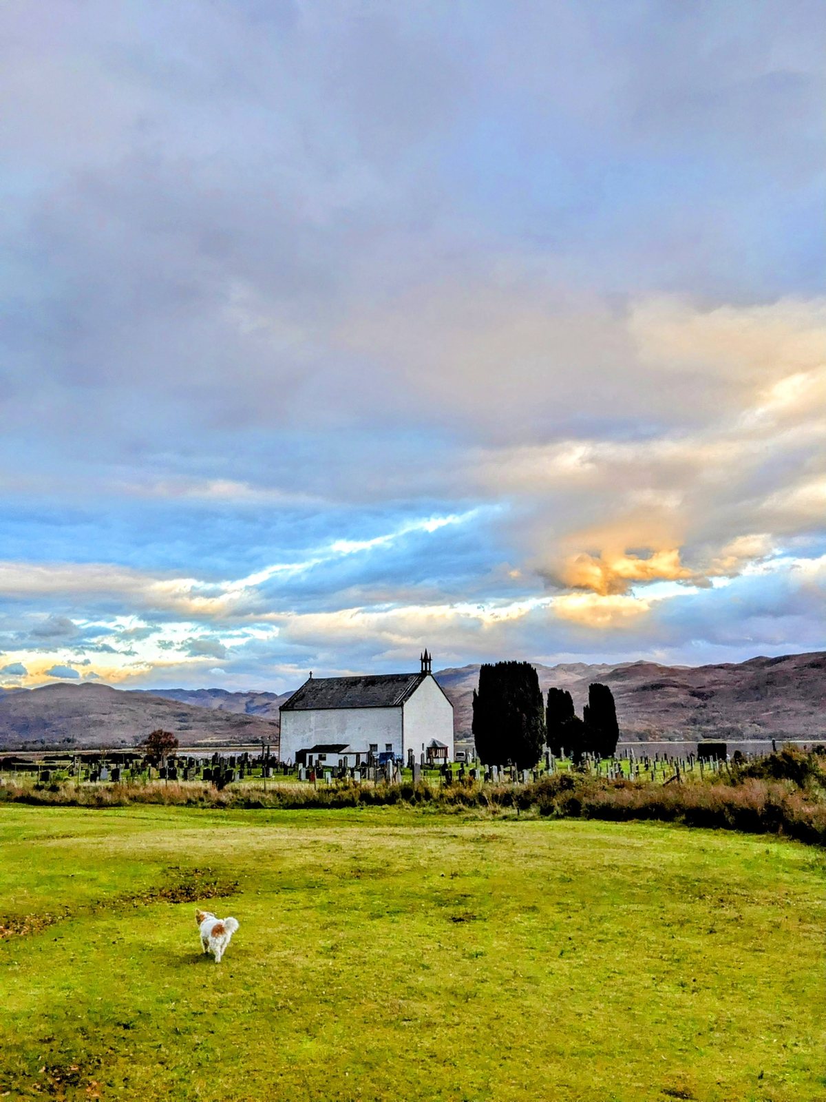 A white house in the wide strath of Strathcarron under big skies.