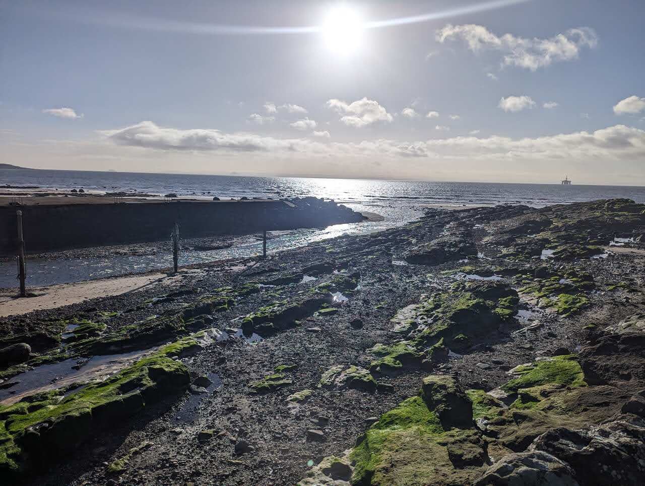 The rocky foreshore at Lower Largo at low tide with a breakwater beyond