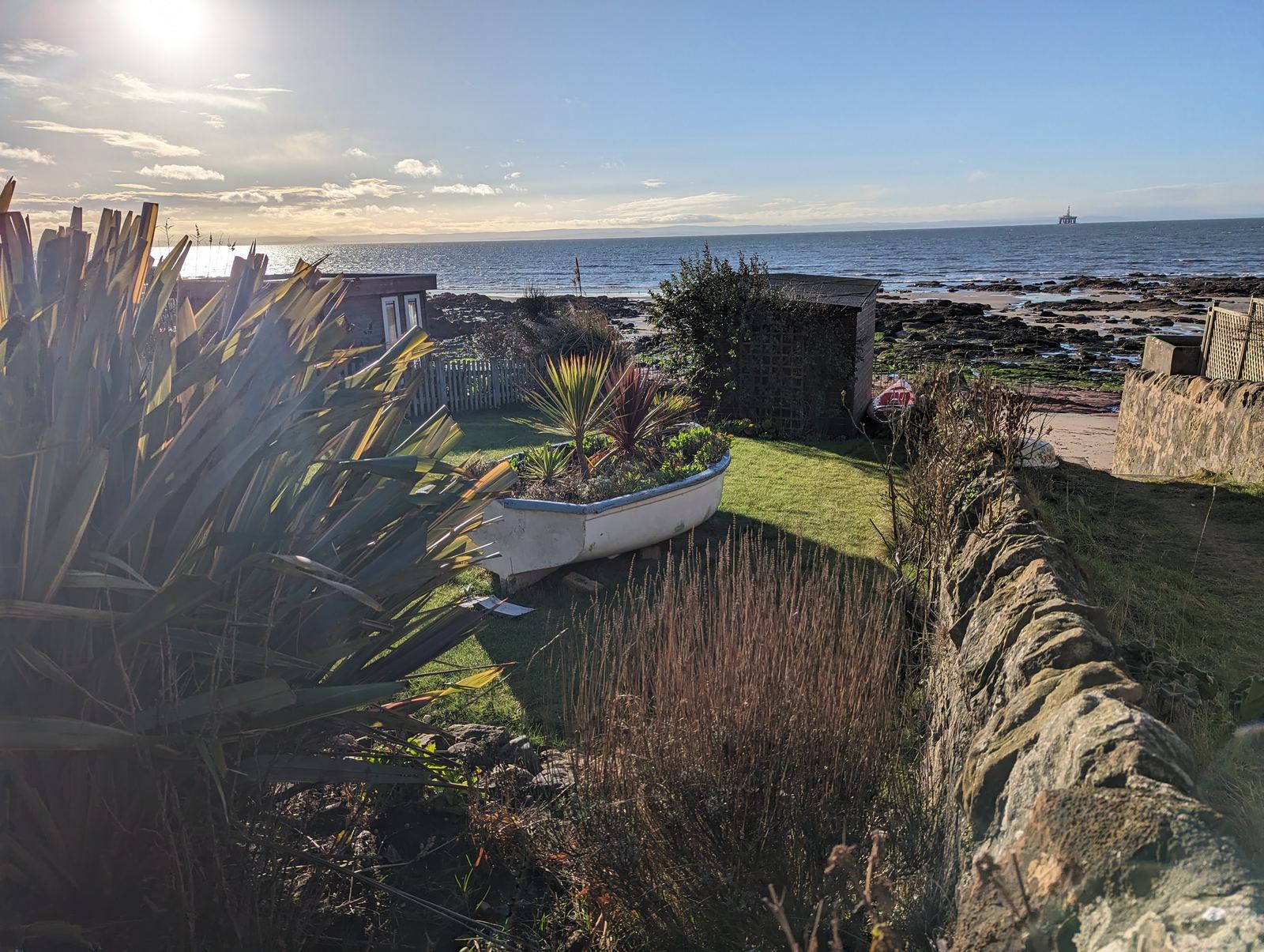A grassy shorefront and old wall above the sea at Lower Largo