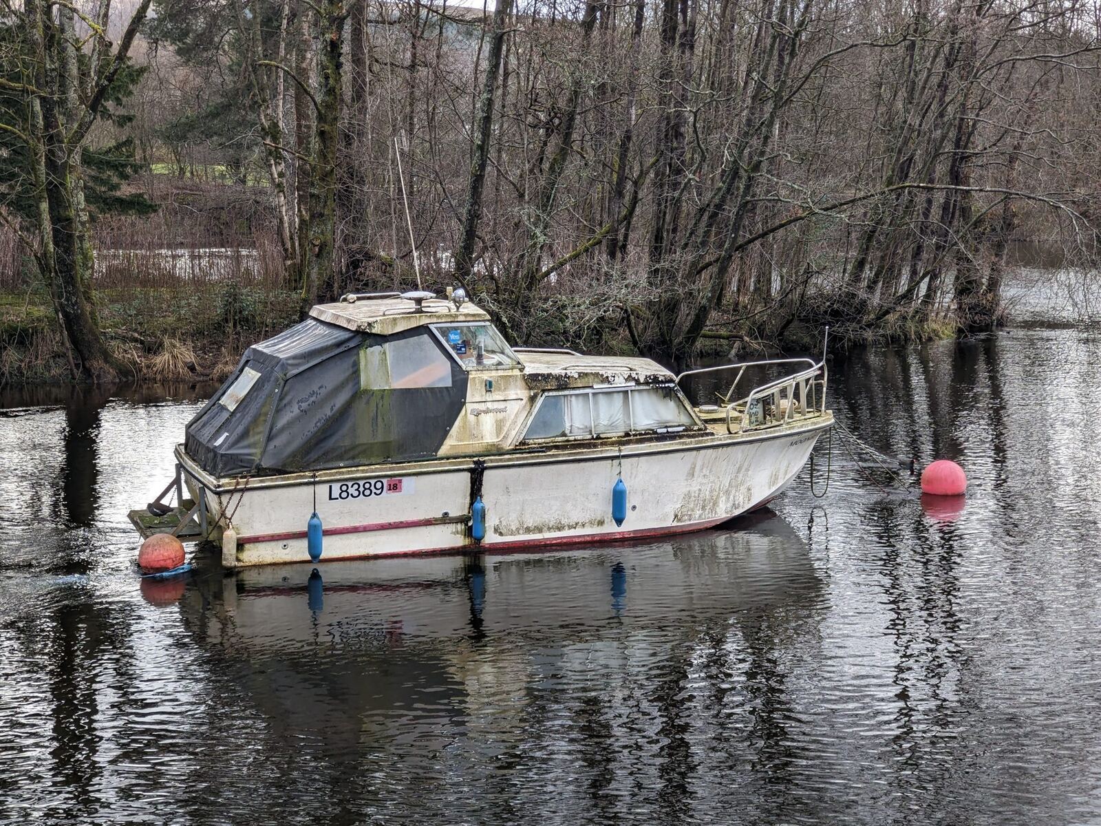 A moored cabin cruiser on the calm River Leven at Balloch, reflections in the water.