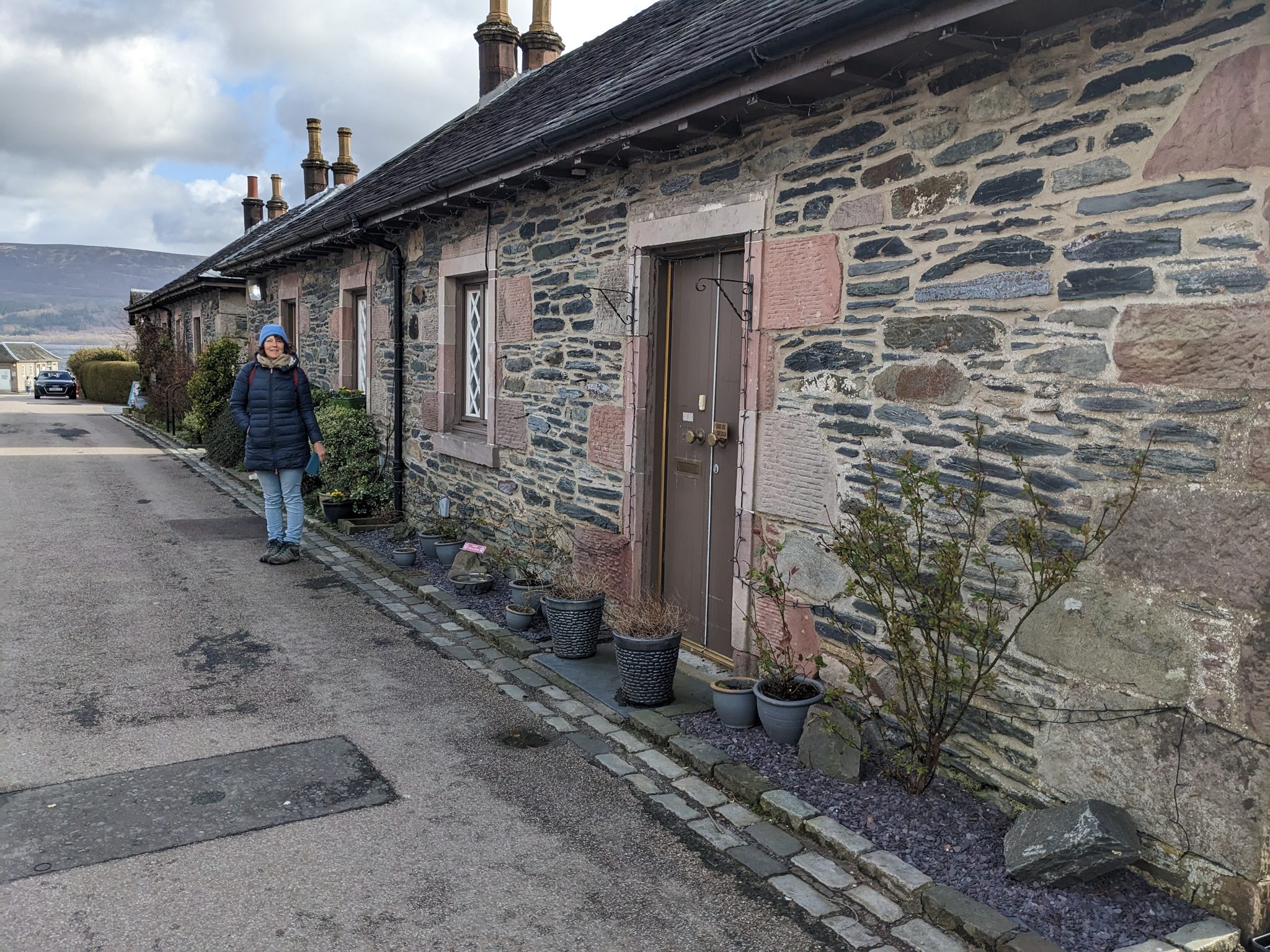 A row of conservation-listed stone cottages at Luss with potted plants along the lane.