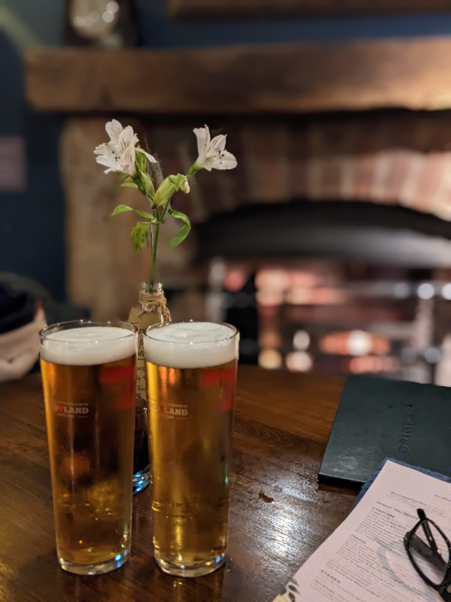 A cosy fireplace and two pints on a table inside a Luss inn.
