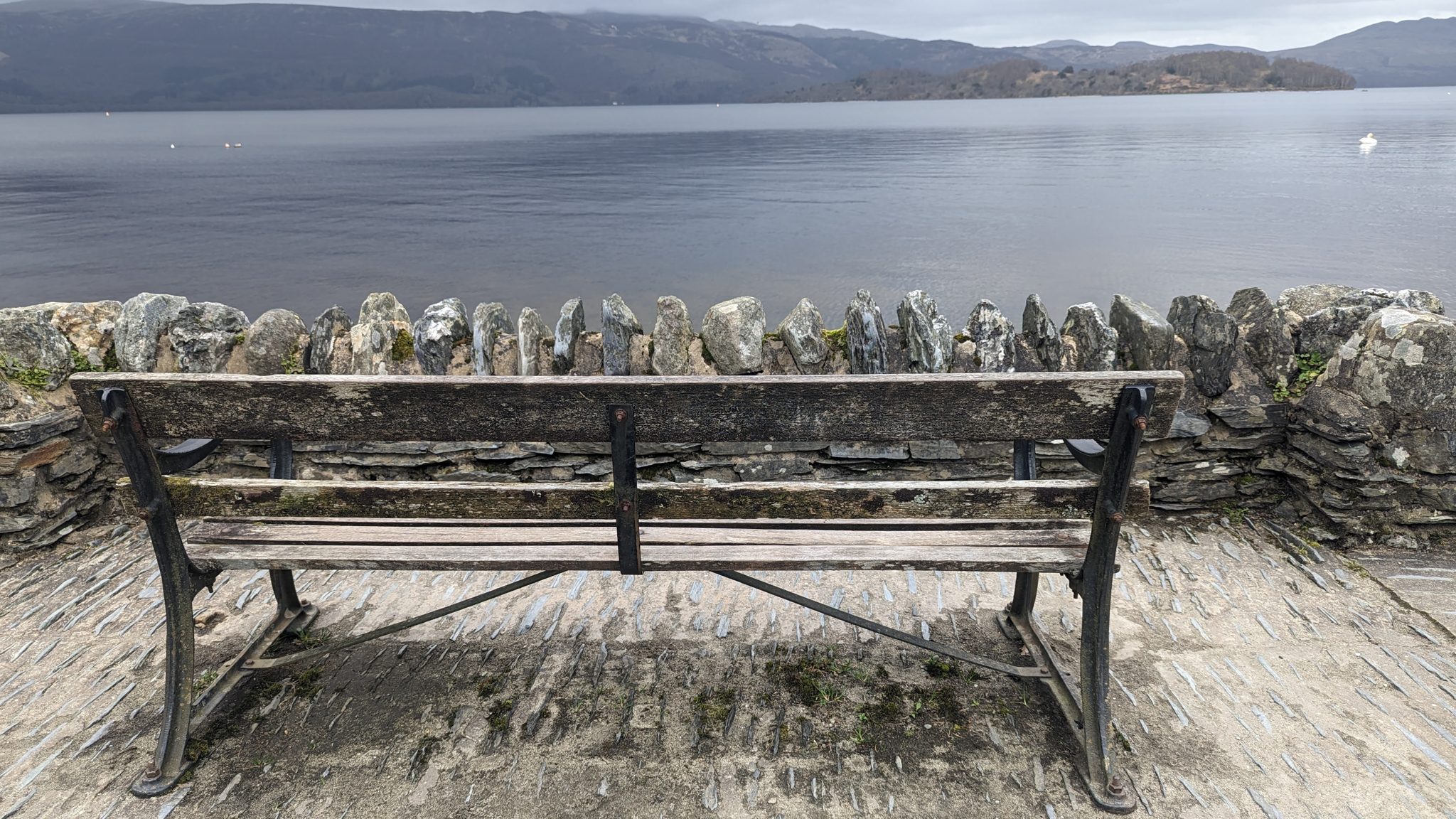 A row of old recumbent grave slabs propped along a wall at Luss churchyard.