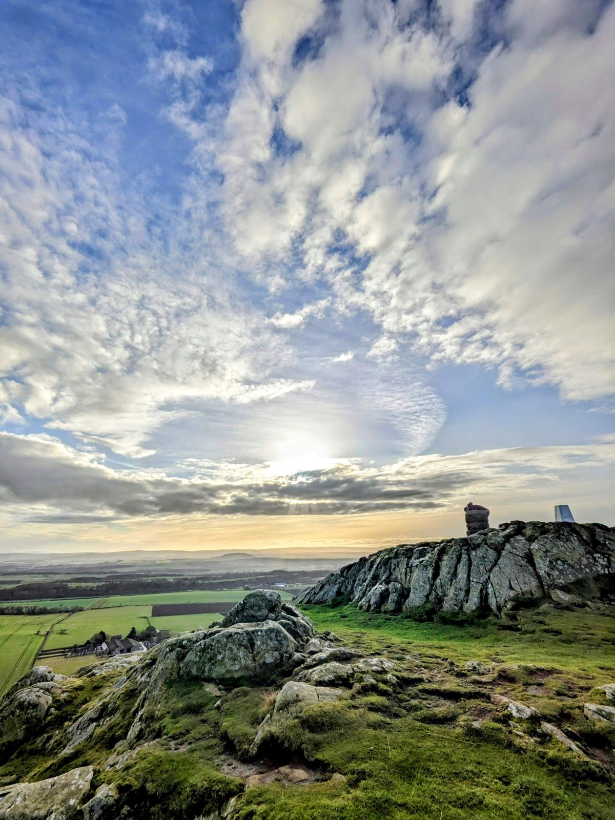 The rocky summit of North Berwick Law with the trig point and old beacon cairn at sunset, looking over East Lothian.