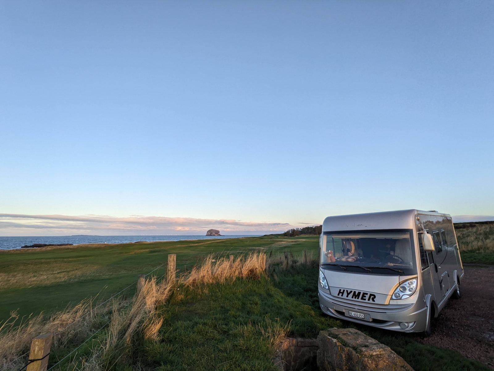 A Hymer motorhome parked on the grassy clifftop at North Berwick, the sea and coastline stretching away beyond.
