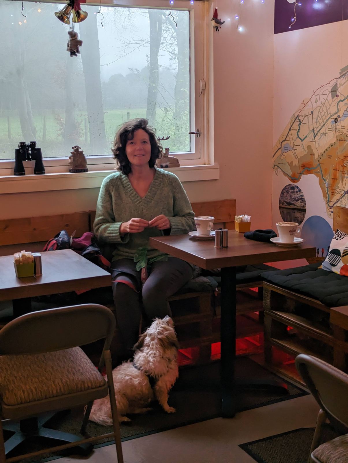A woman and her dog inside the dog-friendly Pentland Hills Cafe at Flotterstone on a wet day.