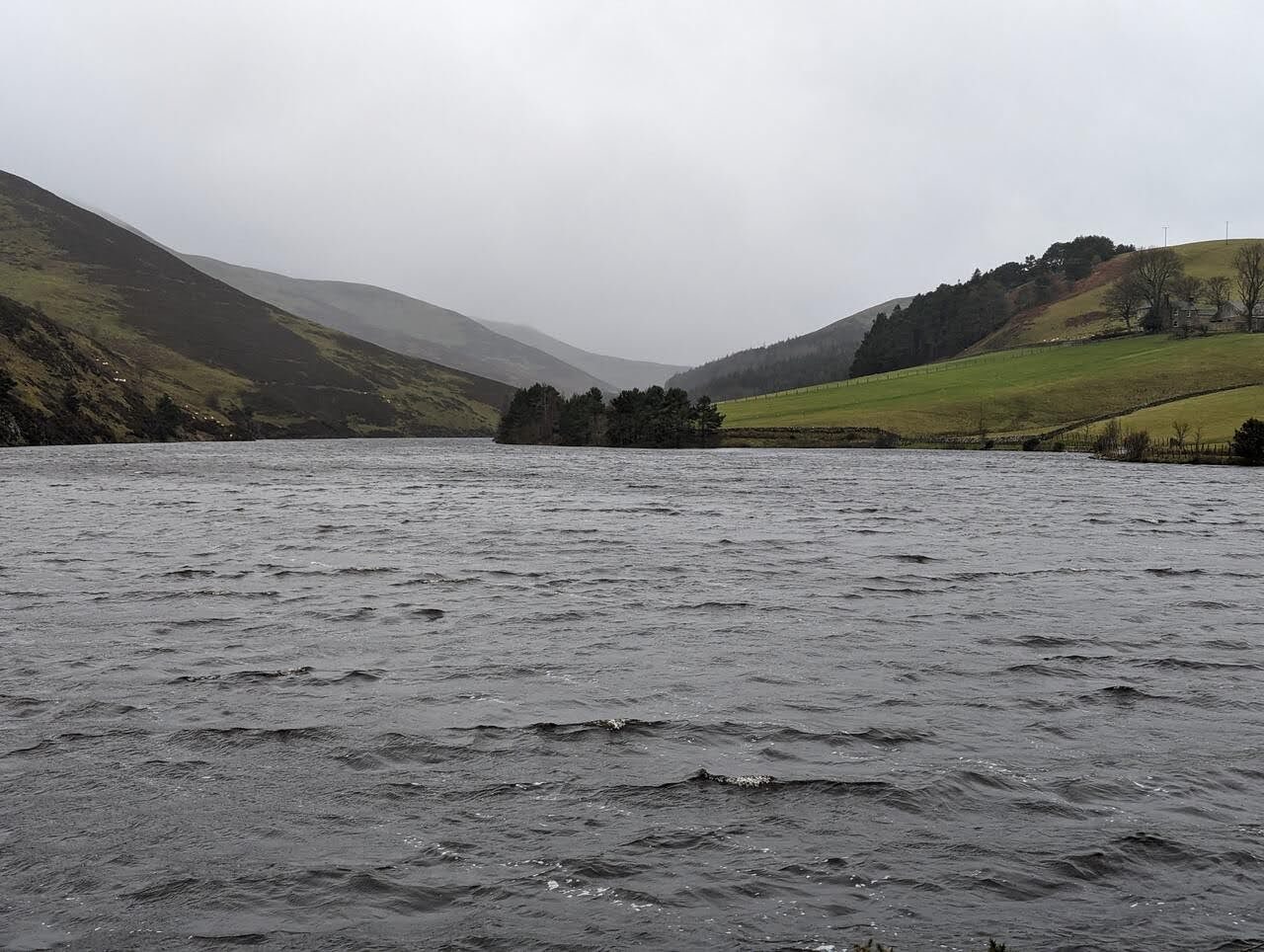 The grey winter water of Glencorse Reservoir in the Pentland Hills with bare hills rising into low cloud.