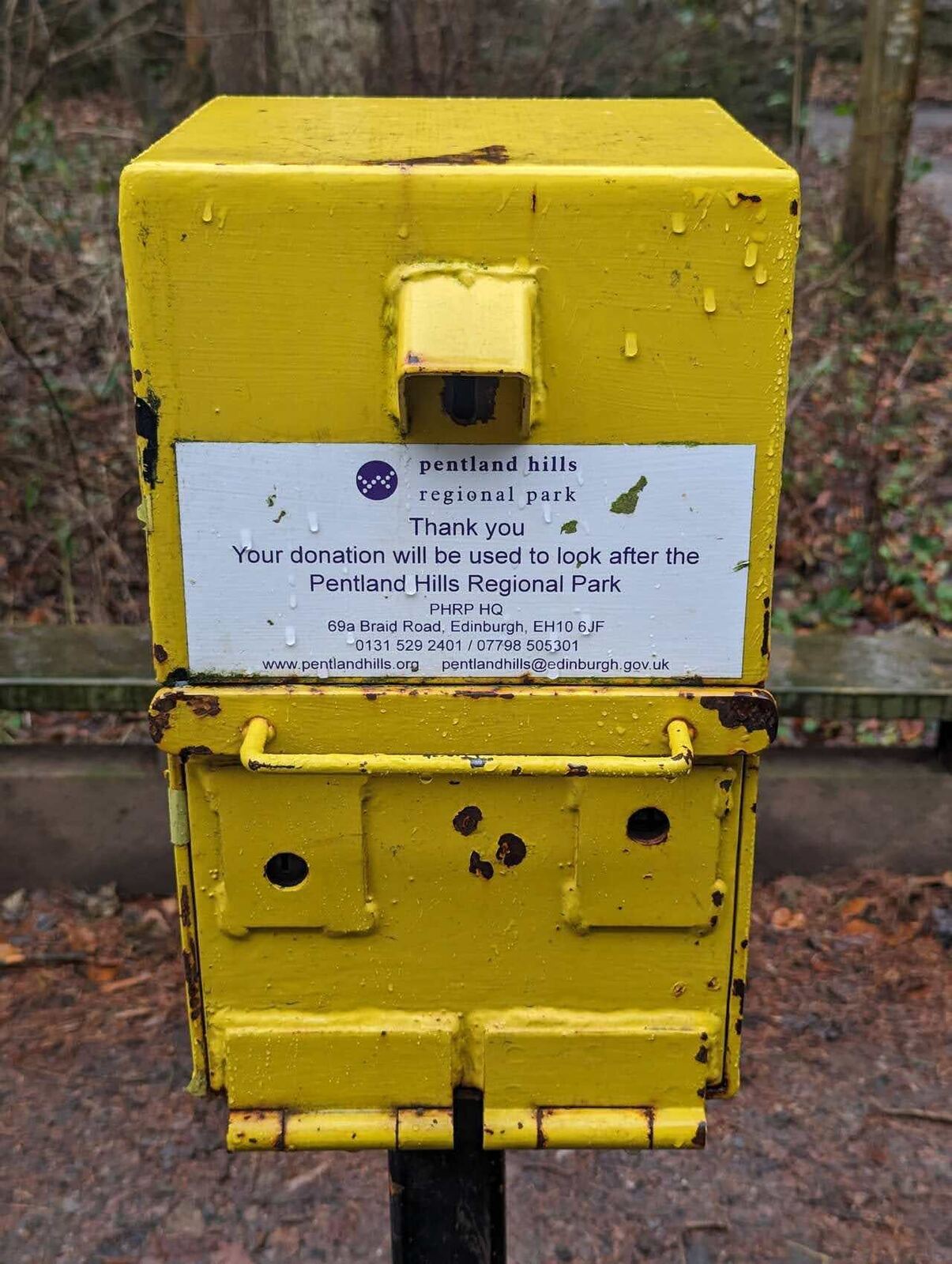 A yellow honesty donation box for the Pentland Hills Regional Park, asking for contributions to look after the park.