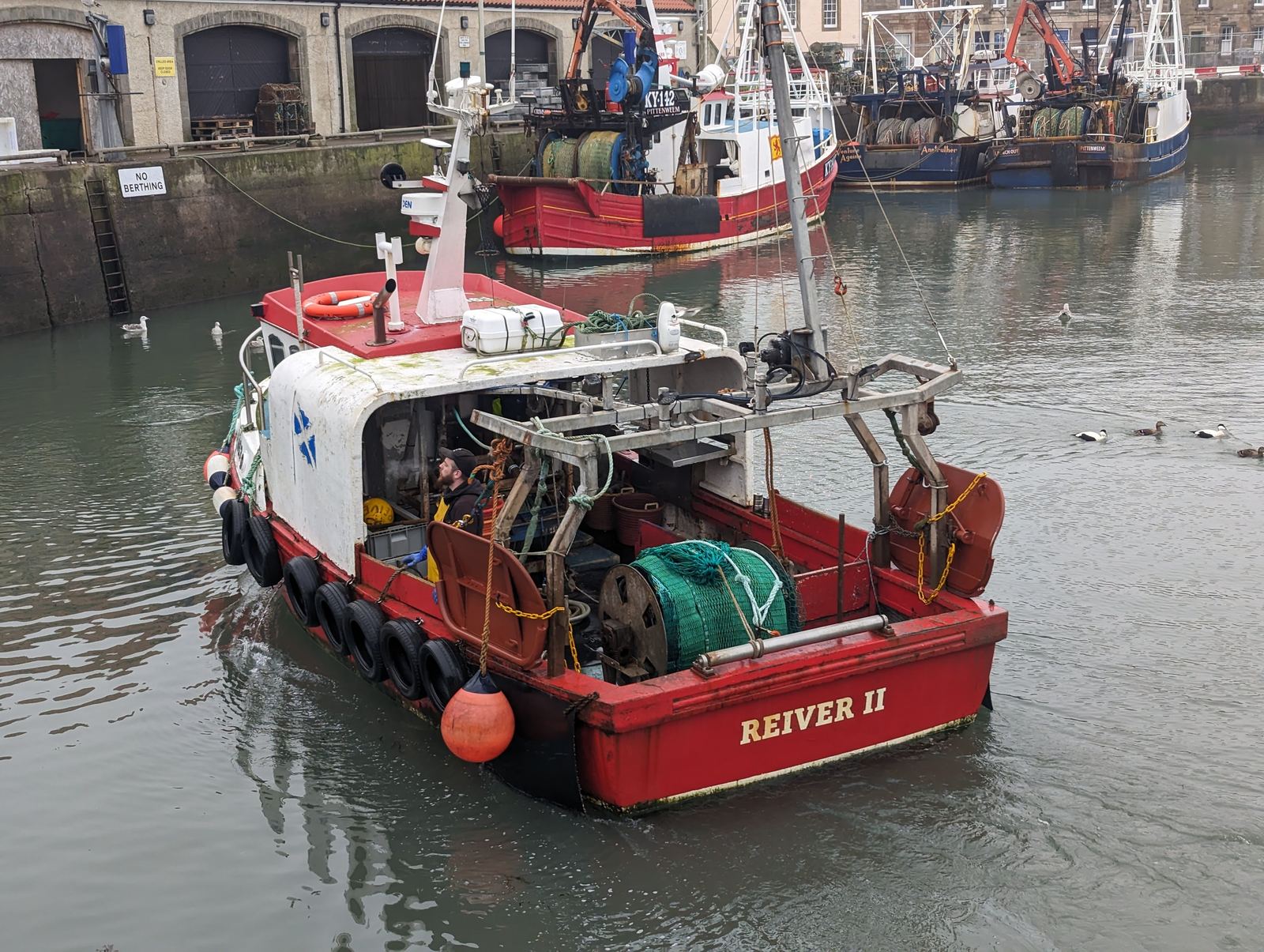 A red fishing boat manoeuvring in Pittenweem harbour