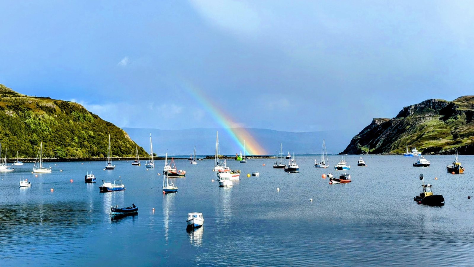 Boats in Portree harbour under a rainbow.