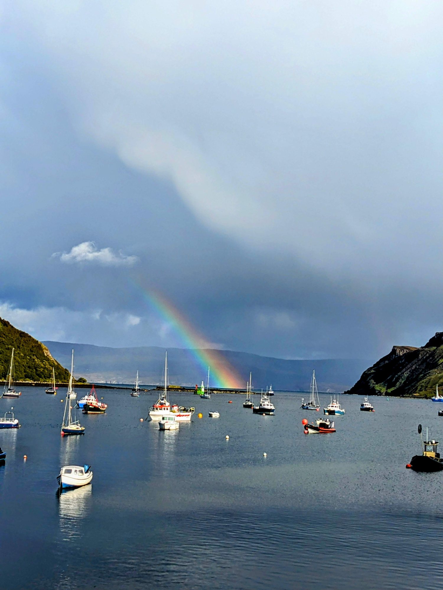 A rainbow over the colourful houses and boats of Portree harbour, Skye.