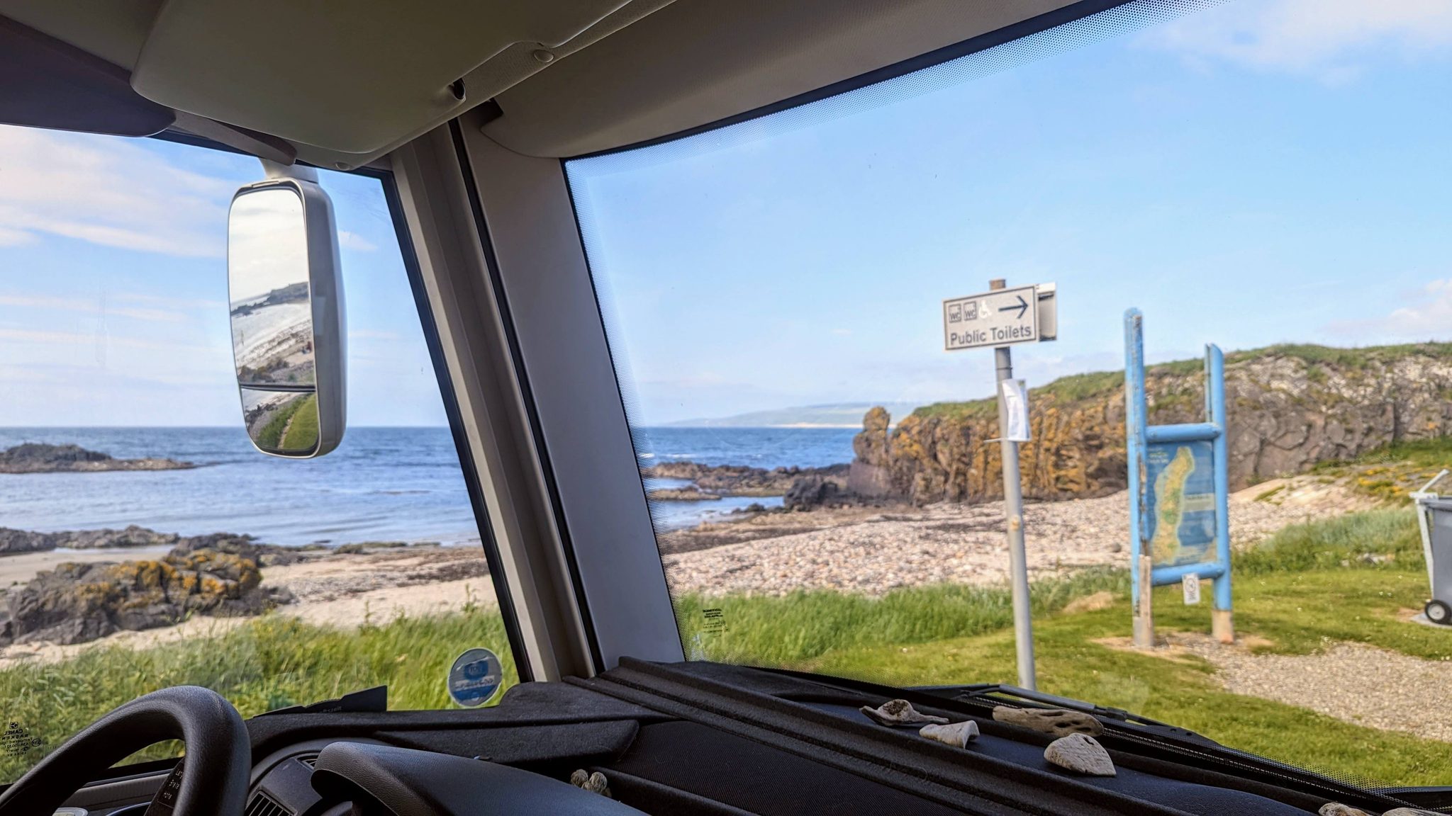 View from the motorhome cab at Southend looking out to the beach and a signpost by the shore.