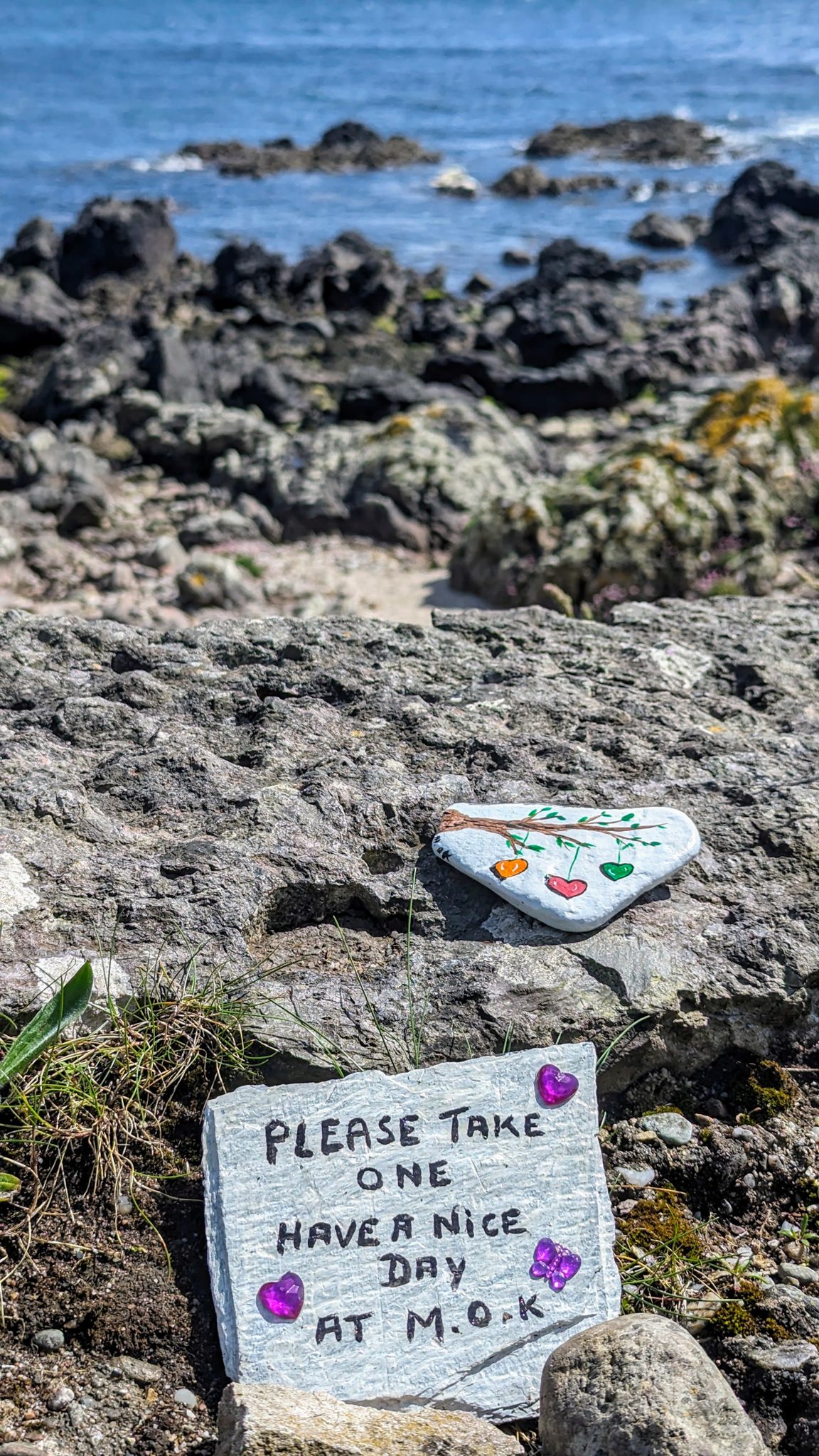 Small hand-painted kindness rocks left among the stones on the shore at Southend, Kintyre.