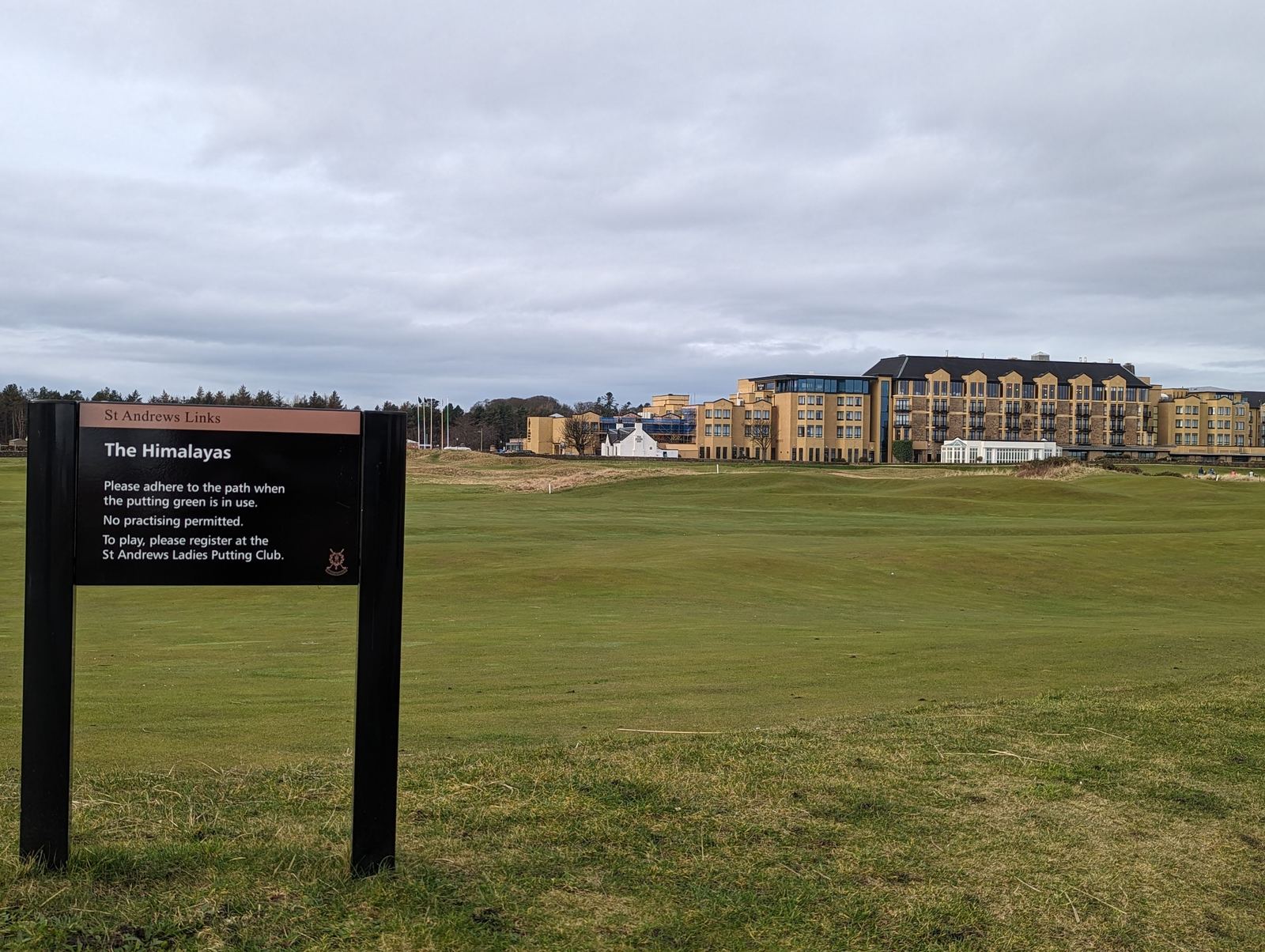 The green fairways of the Old Course links at St Andrews, hotels behind.