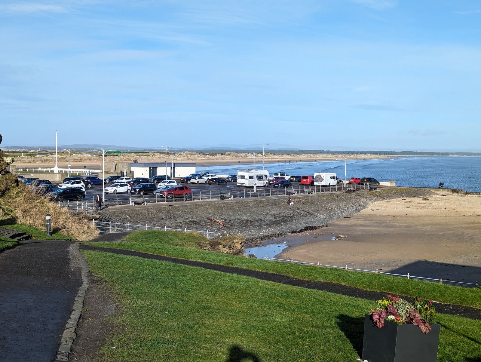 A seafront car park at St Andrews with motorhomes, the beach alongside.