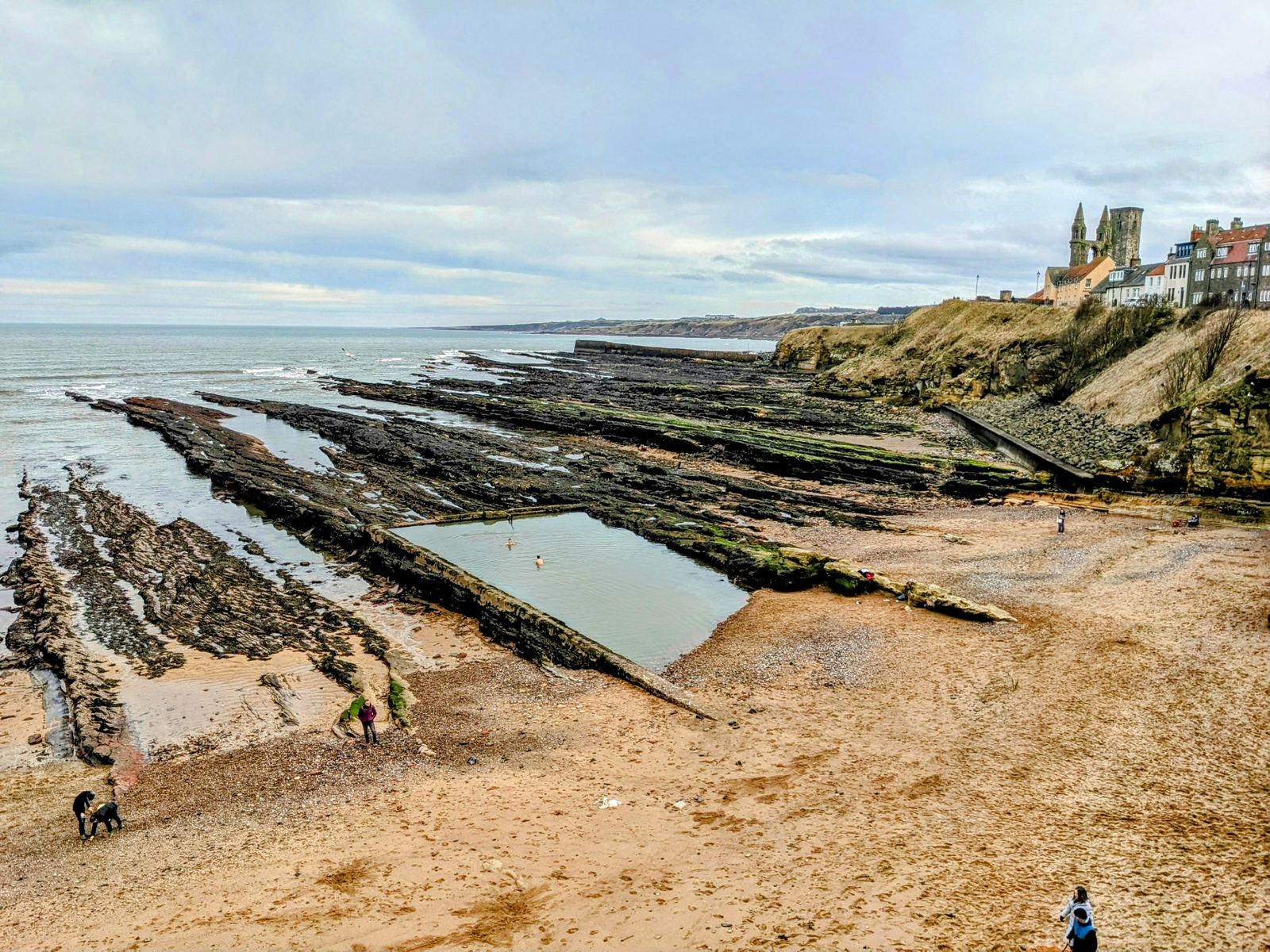 The dramatic wave-cut rock platforms on the shore at St Andrews, the town beyond.