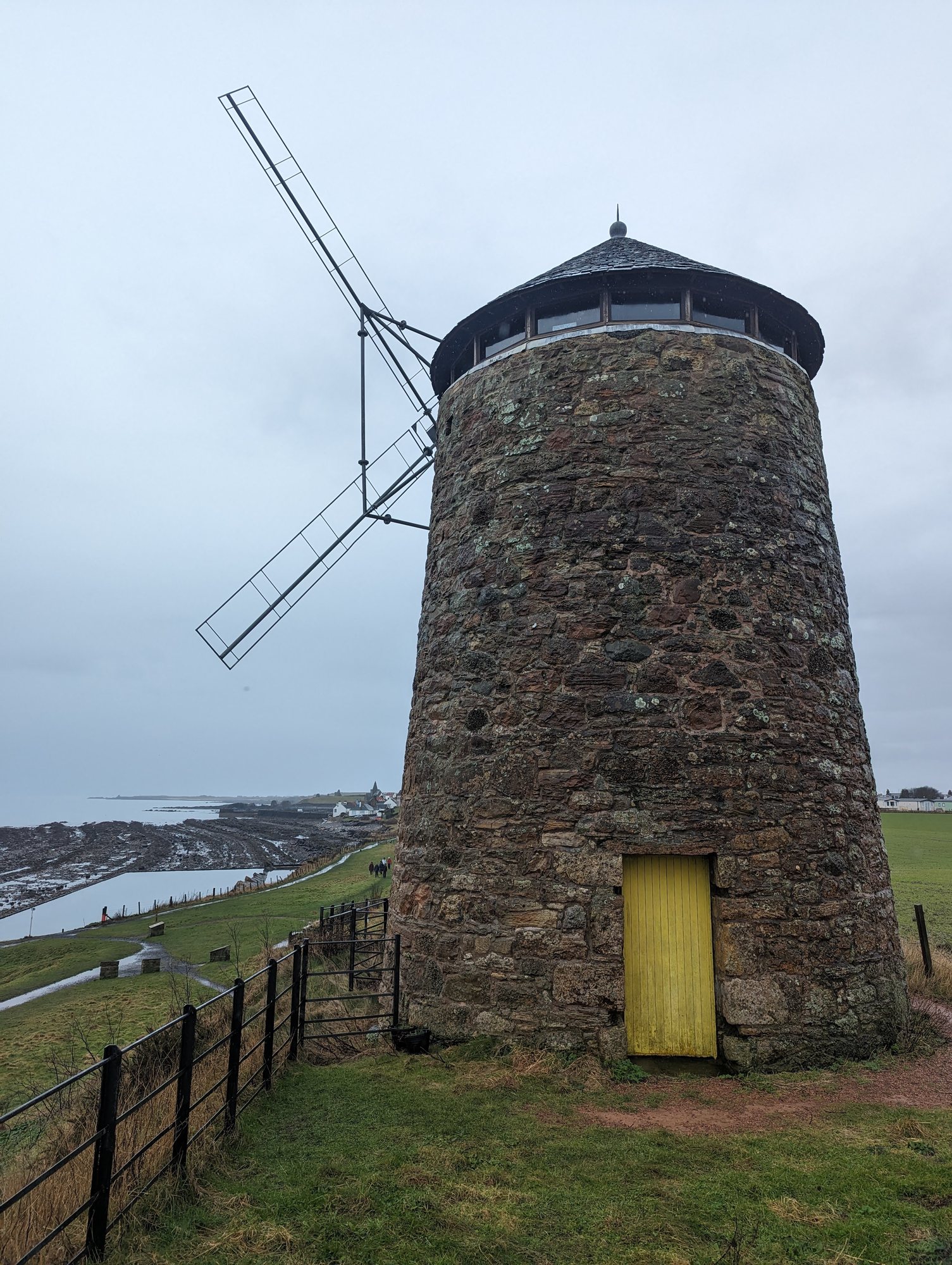 The restored St Monans windmill with its new sails, shore beyond.