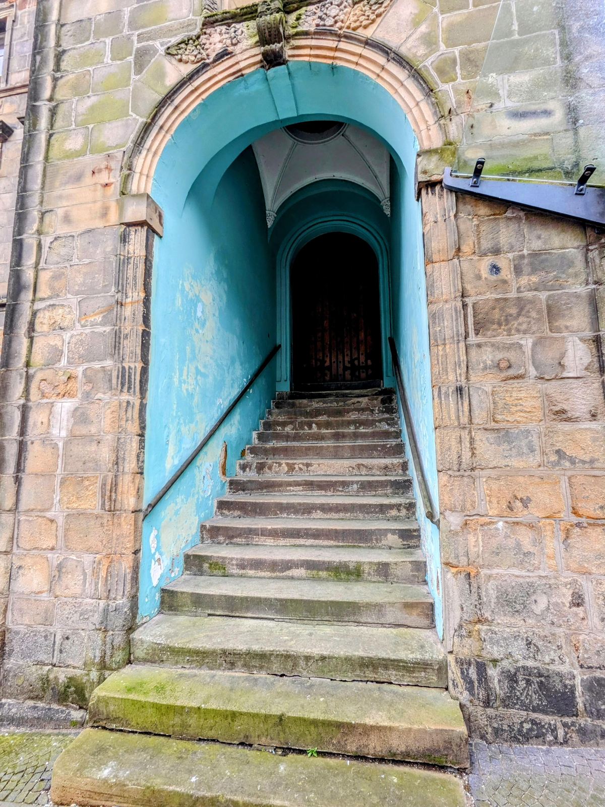 A narrow stone close in Stirling's old town with a blue-painted archway and cobbles.