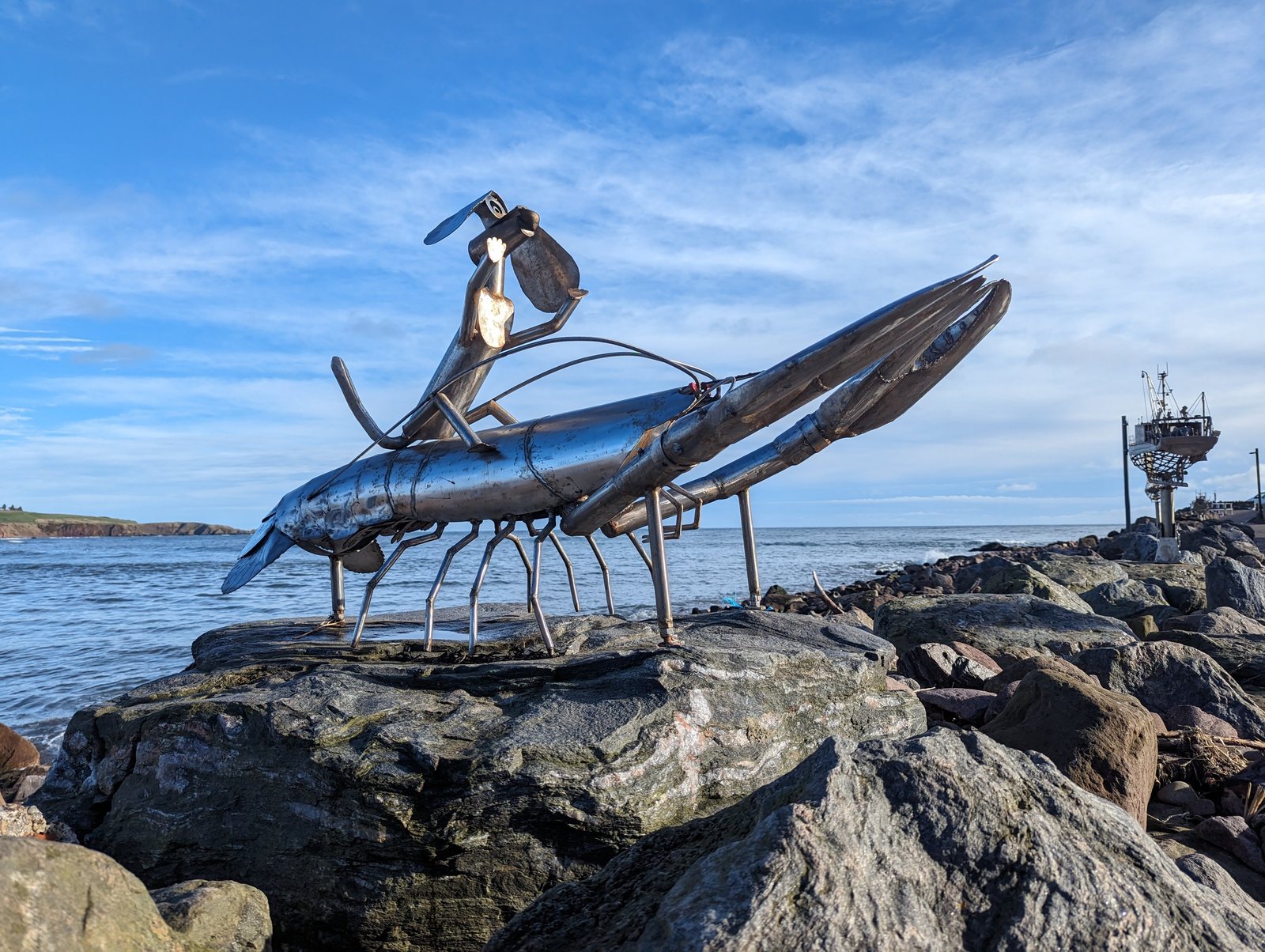 A metal langoustine sculpture with a small figure riding it, Stonehaven.