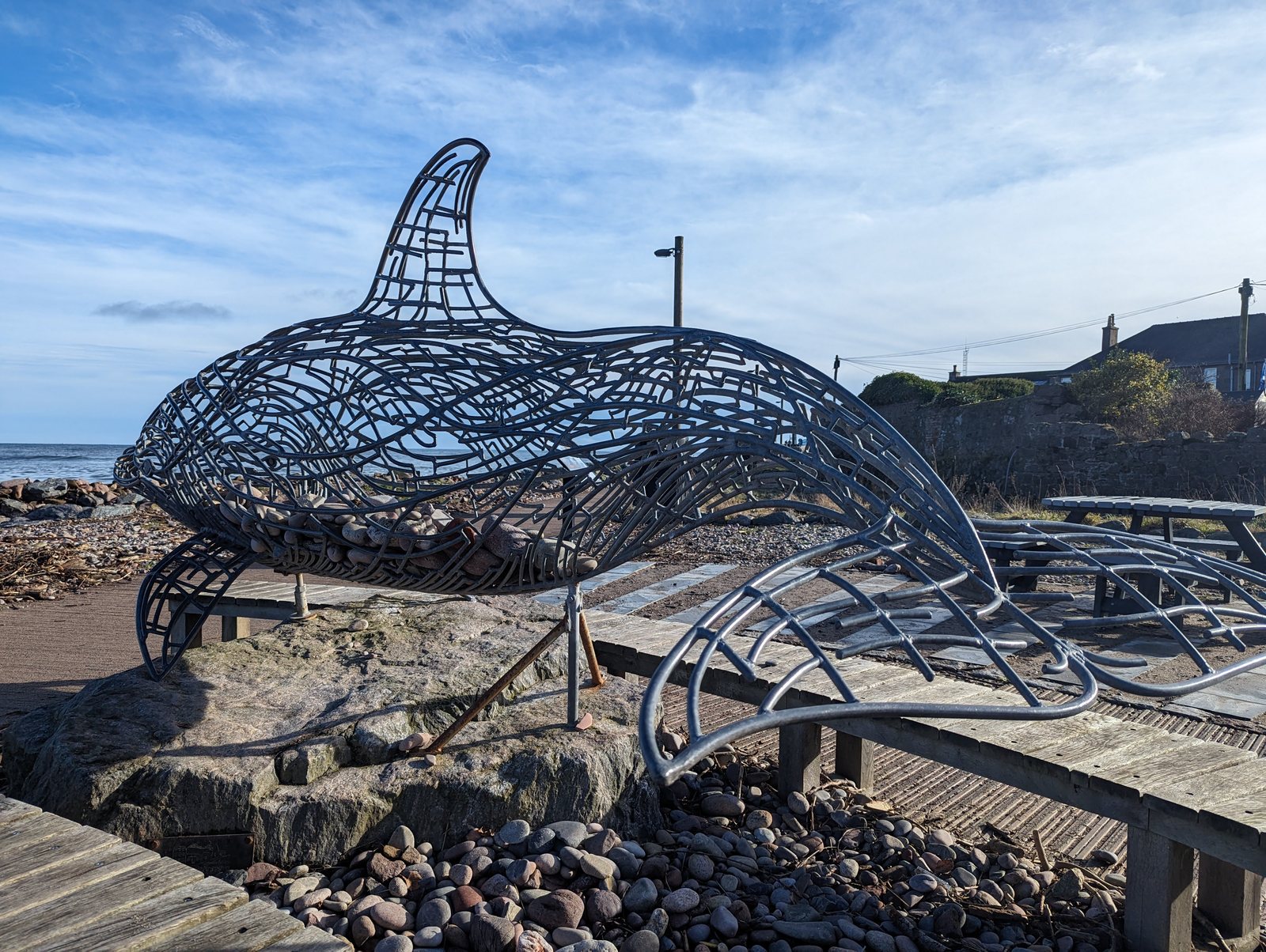A large metal orca sculpture breaching over the boardwalk at Stonehaven.