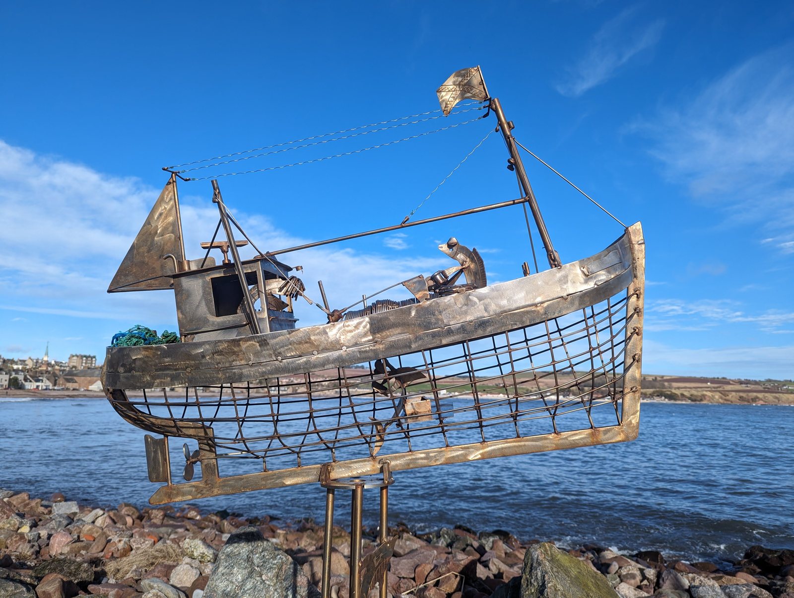 A wire sailing-boat sculpture on the rocks at Stonehaven.