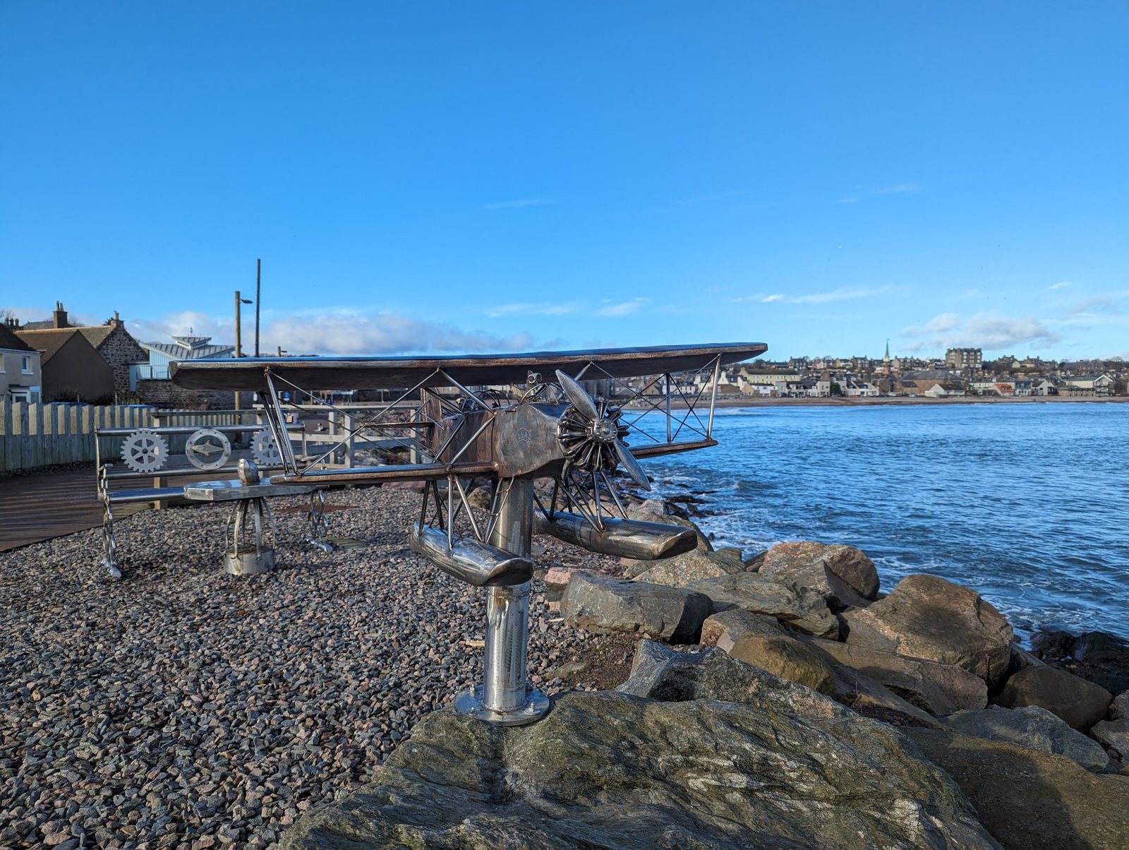 A metal seaplane sculpture on the shoreline rocks at Stonehaven.