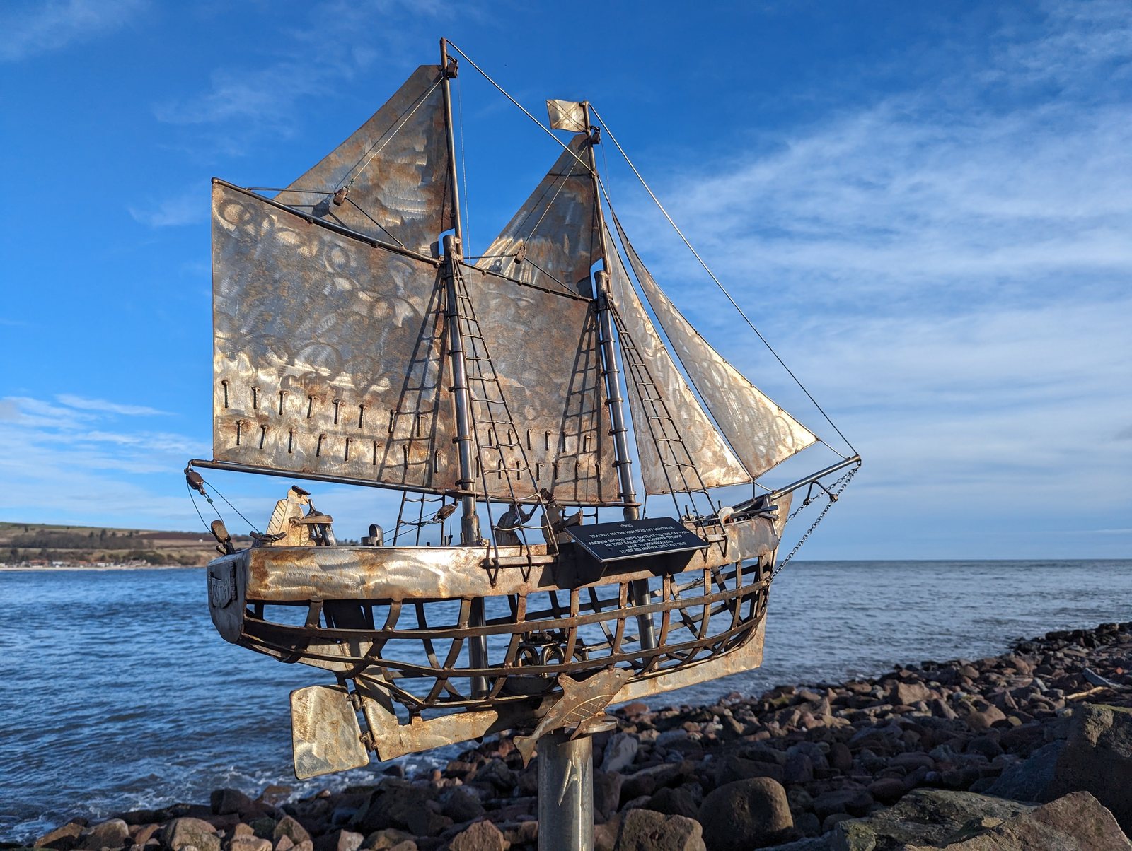 A schooner sculpture with rusted metal sails on the rocks, Stonehaven.