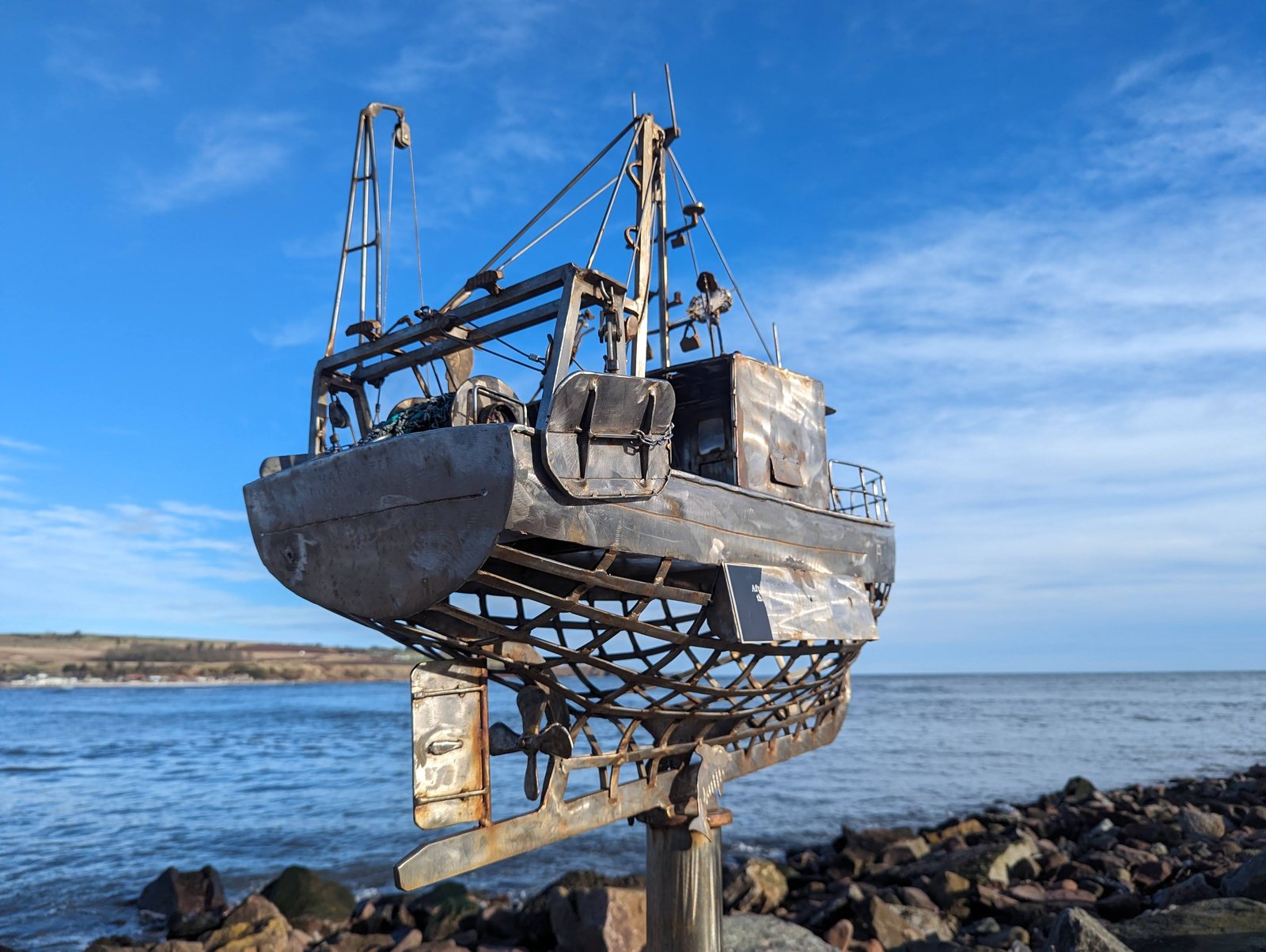 A metal trawler sculpture cantilevered over the rocks at Stonehaven.
