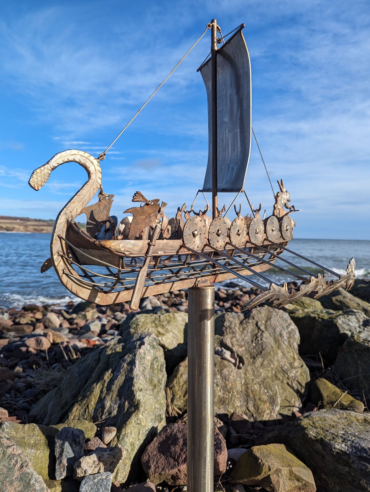 A metal Viking longship sculpture with a dragon prow at Stonehaven shore.