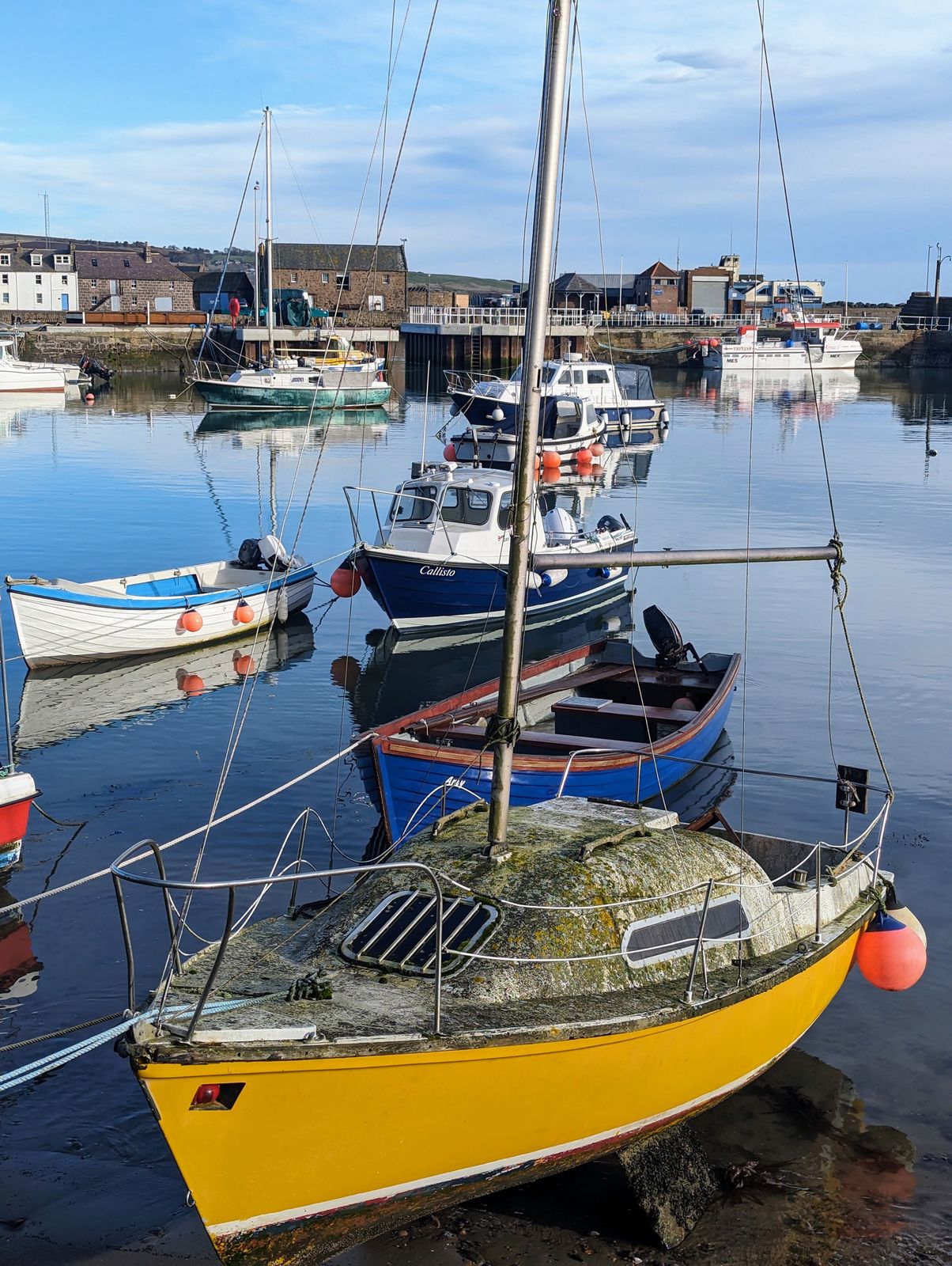 A yellow yacht and fishing boats in Stonehaven harbour.