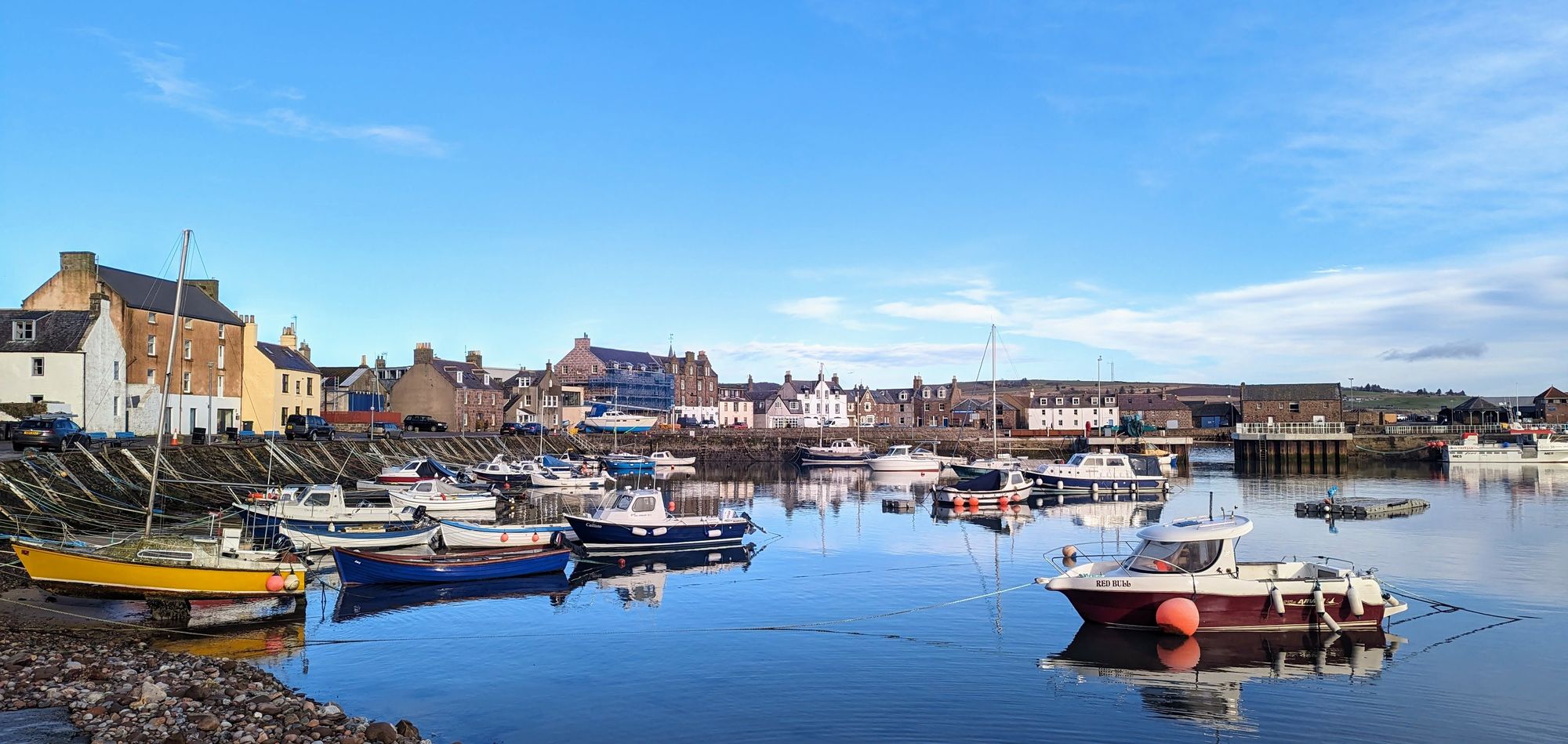 The old fishing harbour at Stonehaven reflected in calm water, Aberdeenshire.